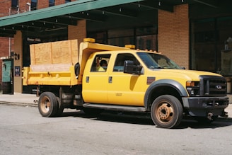 A yellow dump truck parked in front of a building