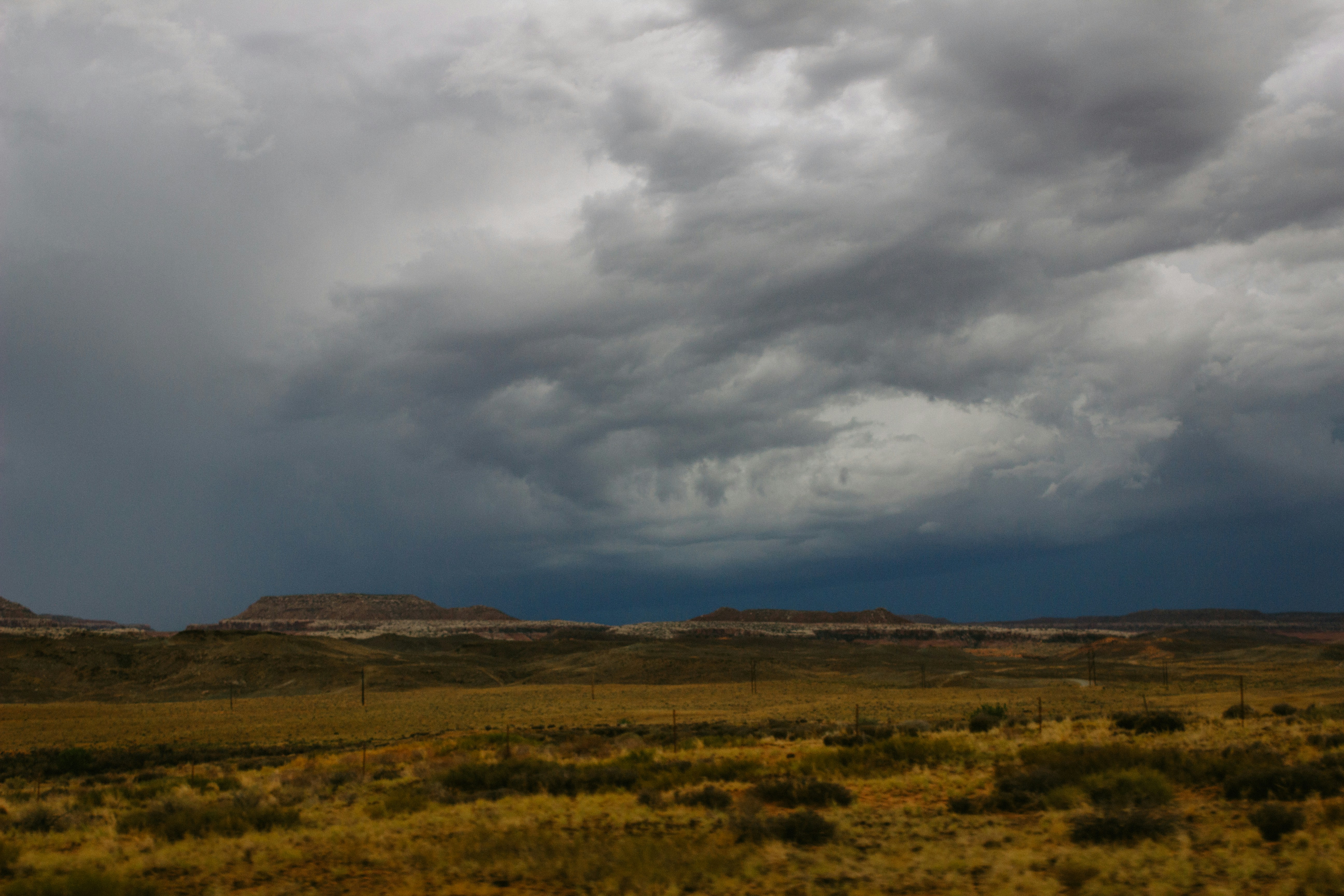 A cloudy sky over a grassy plain with mountains in the distance