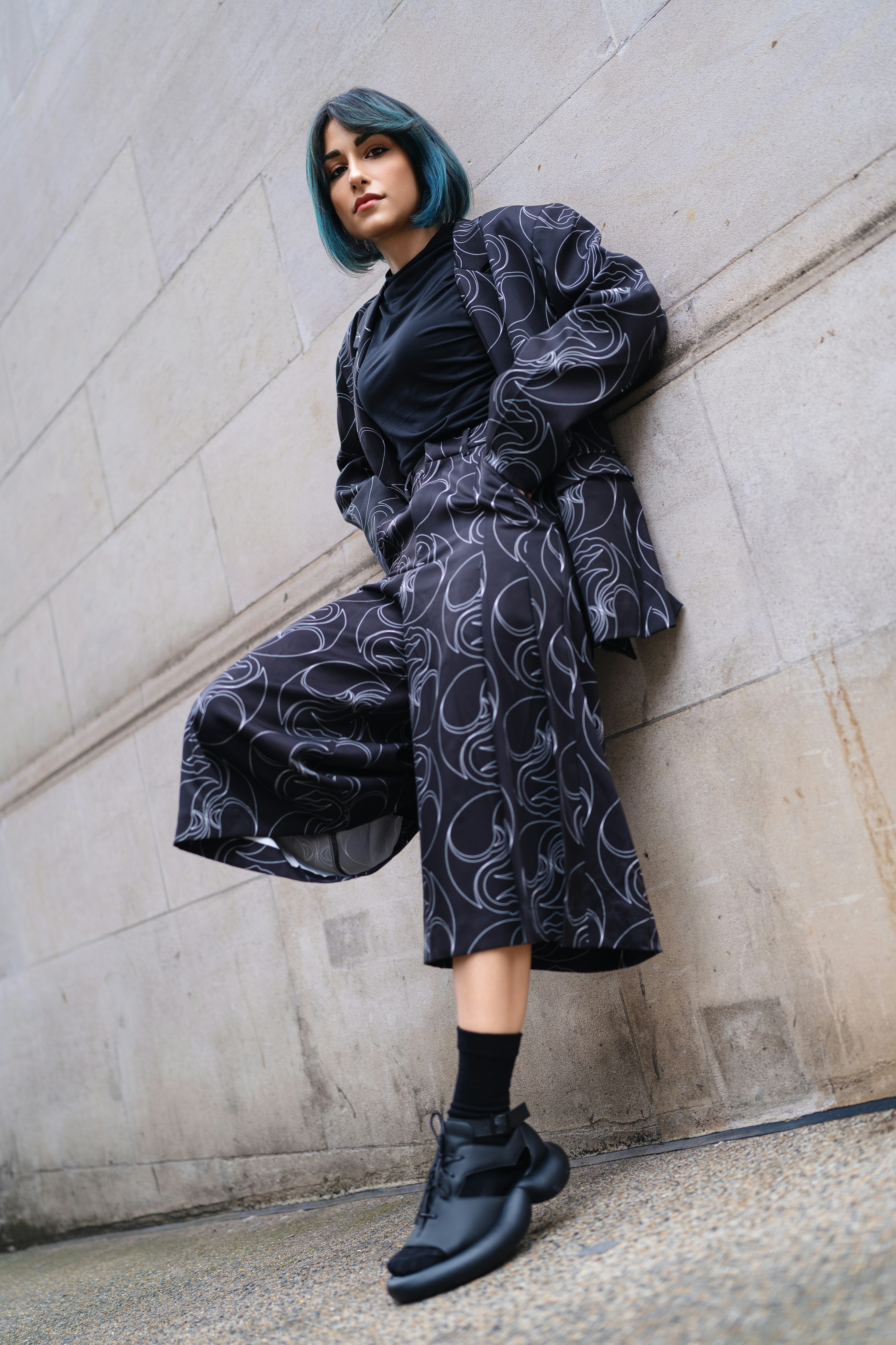A woman leaning against a wall with her legs crossed