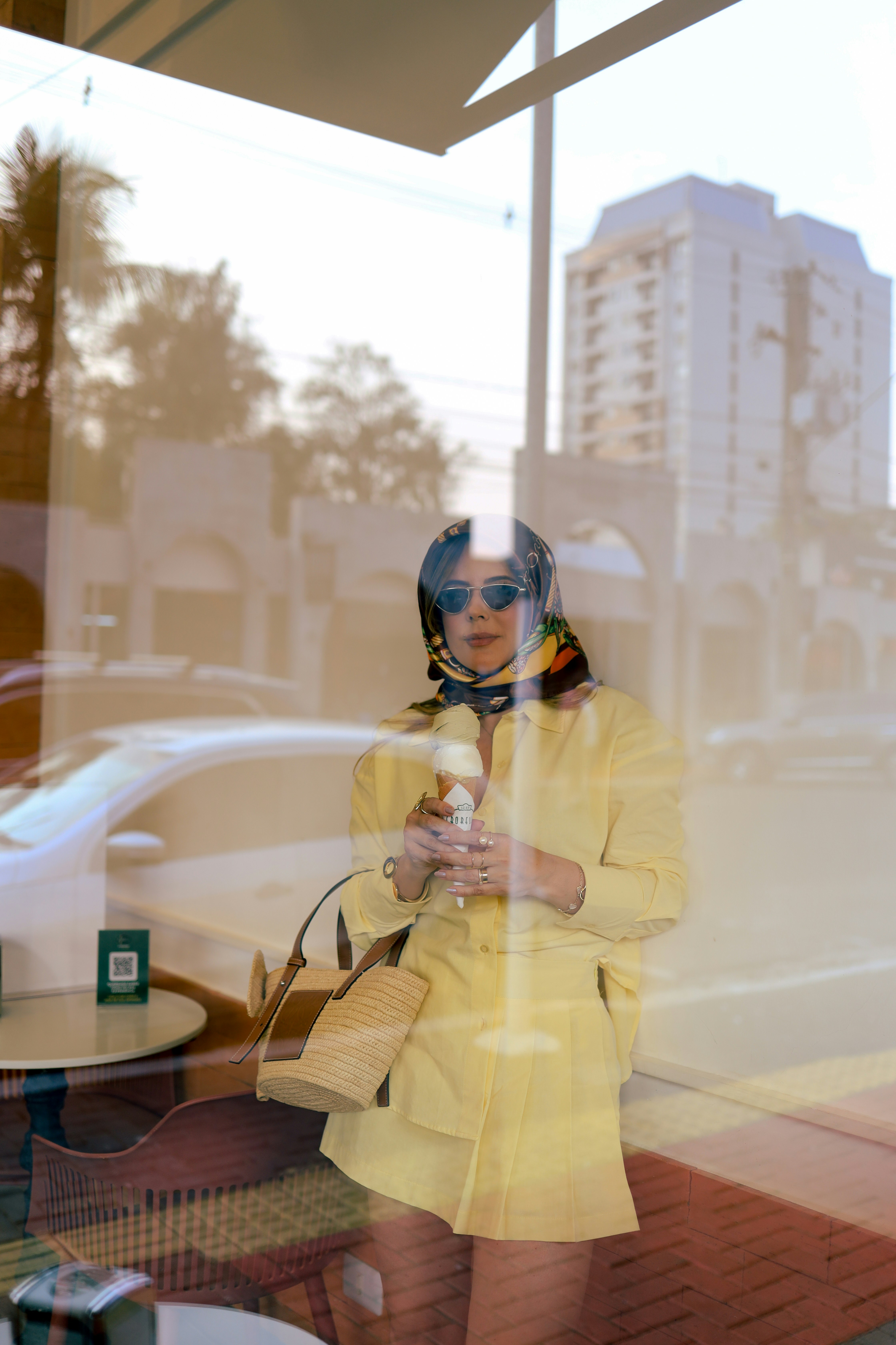 Une femme debout devant une fenêtre tenant un téléphone portable