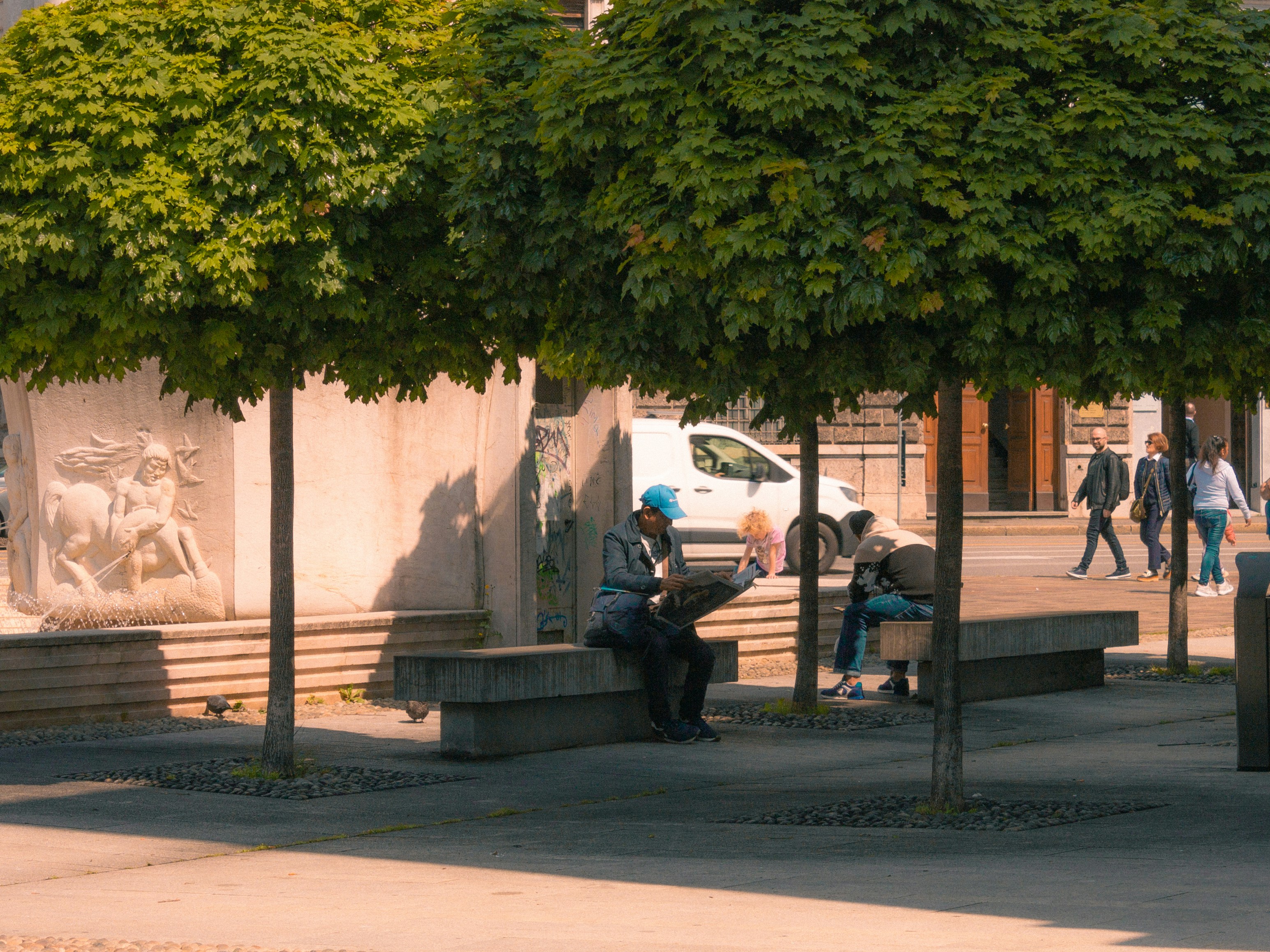 A group of people sitting on a bench under a tree