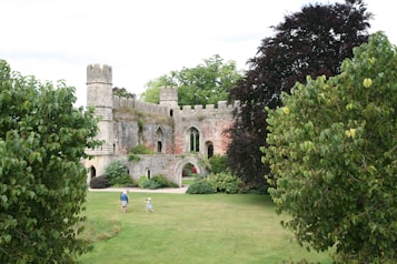 Two people are walking through the trees in front of a castle