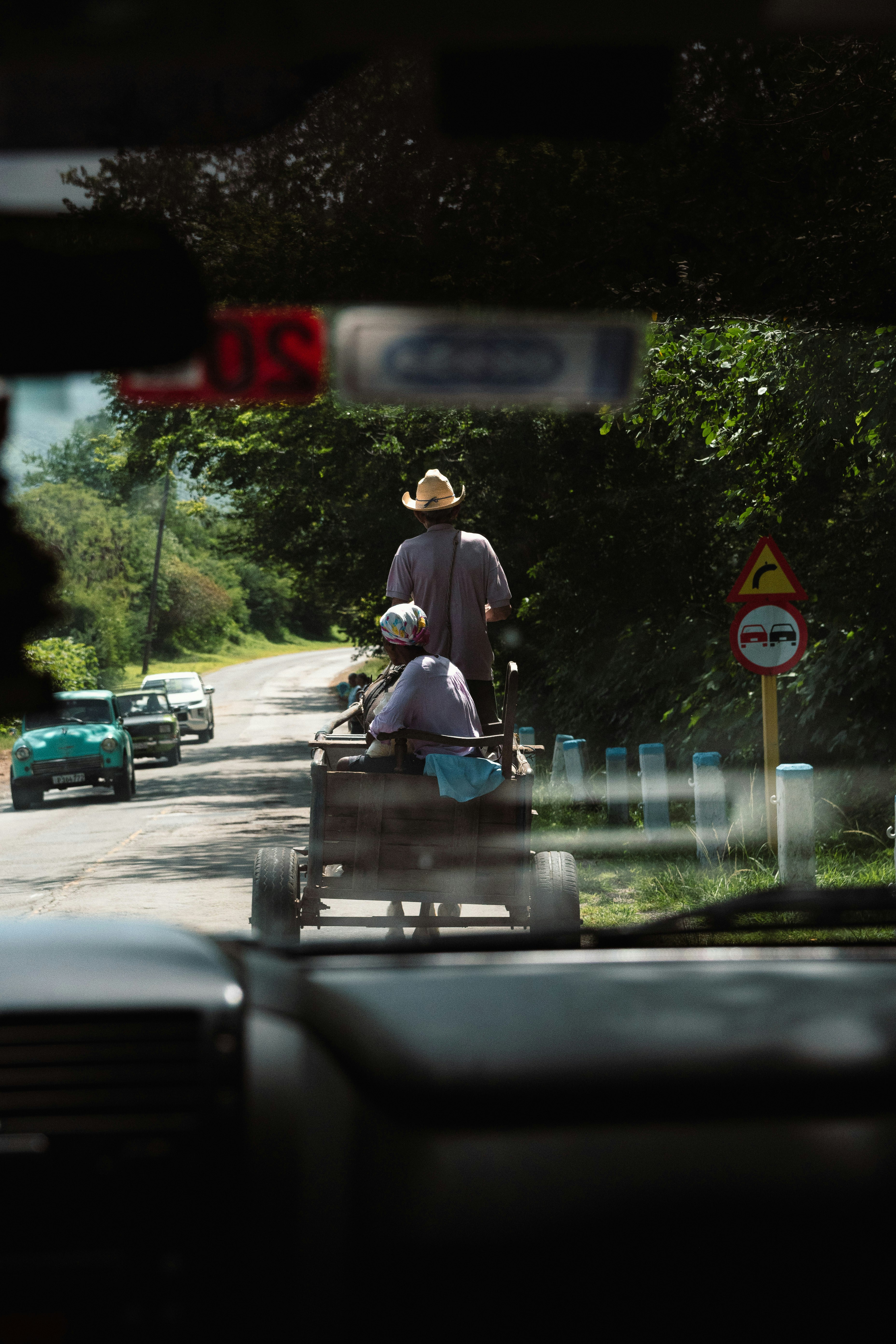 A man riding a cart down a street next to a forest