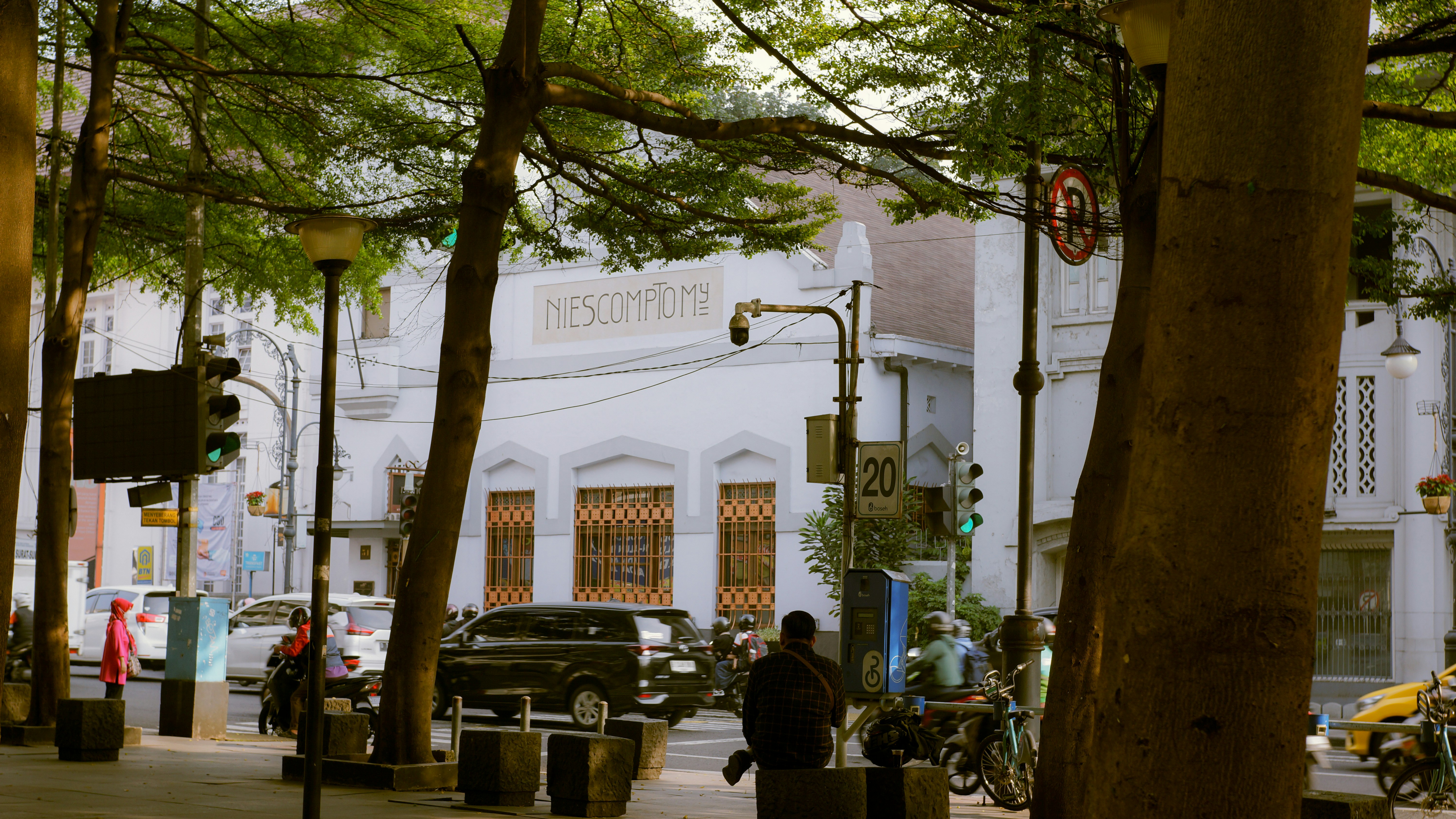 Un uomo che cammina lungo una strada accanto ad alberi alti