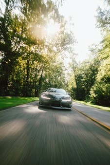 A car driving down a road with trees in the background