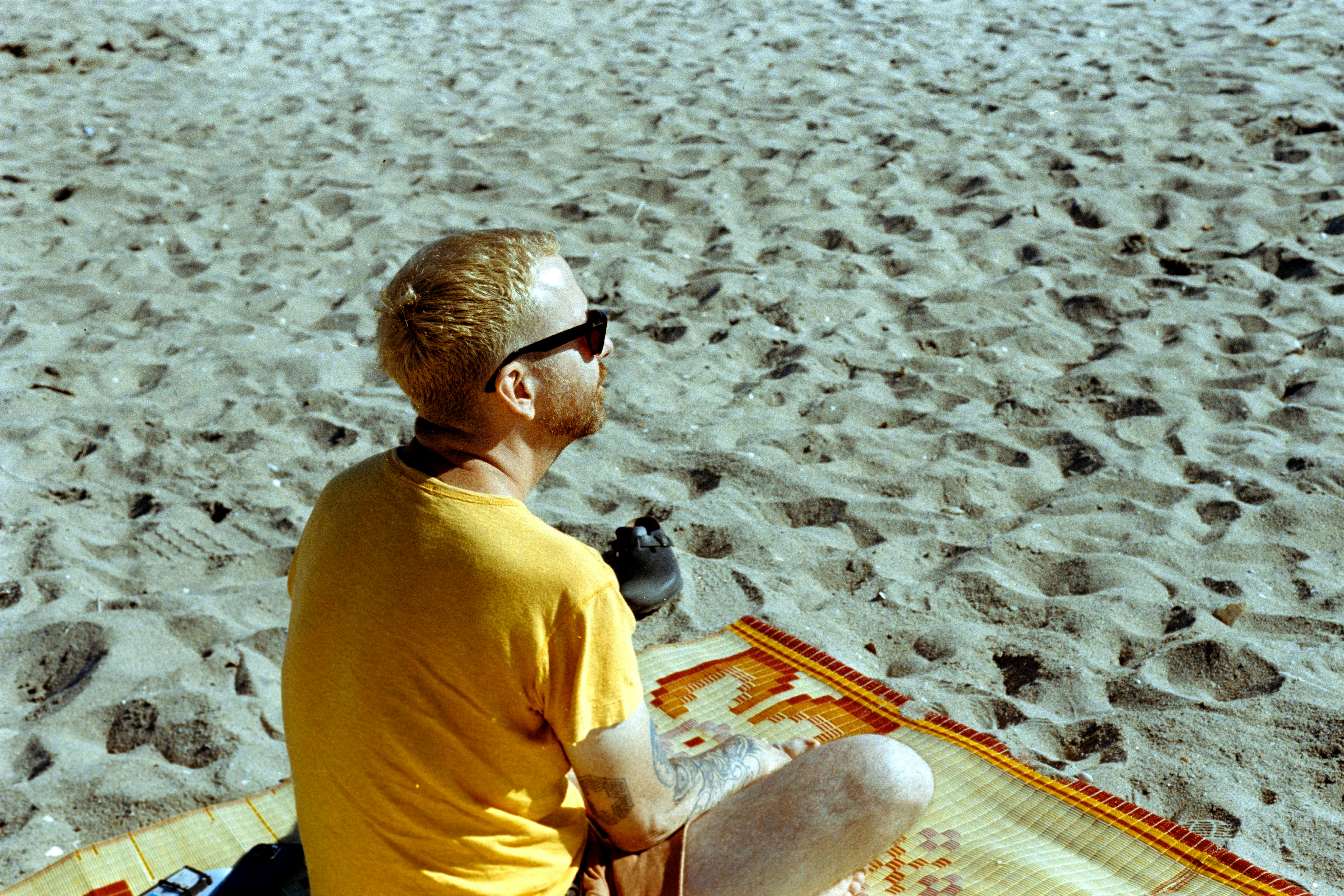 A man sitting on top of a blanket on top of a beach