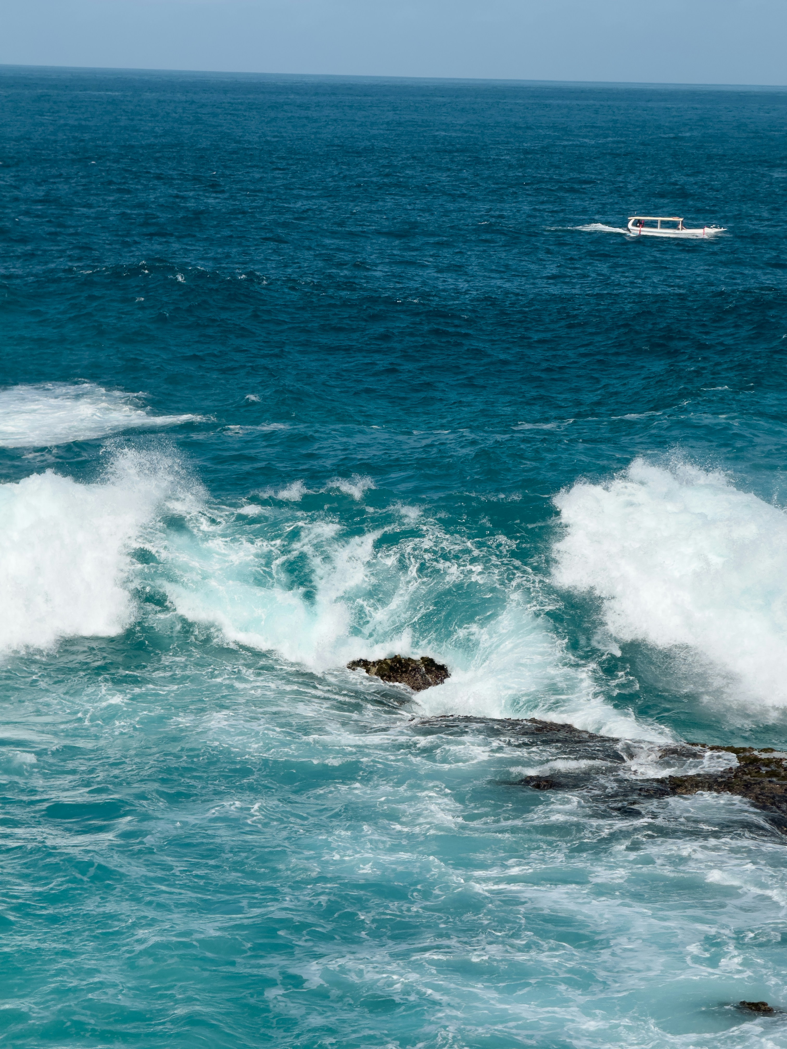 Un bateau est dans l’eau près d’un rivage rocheux