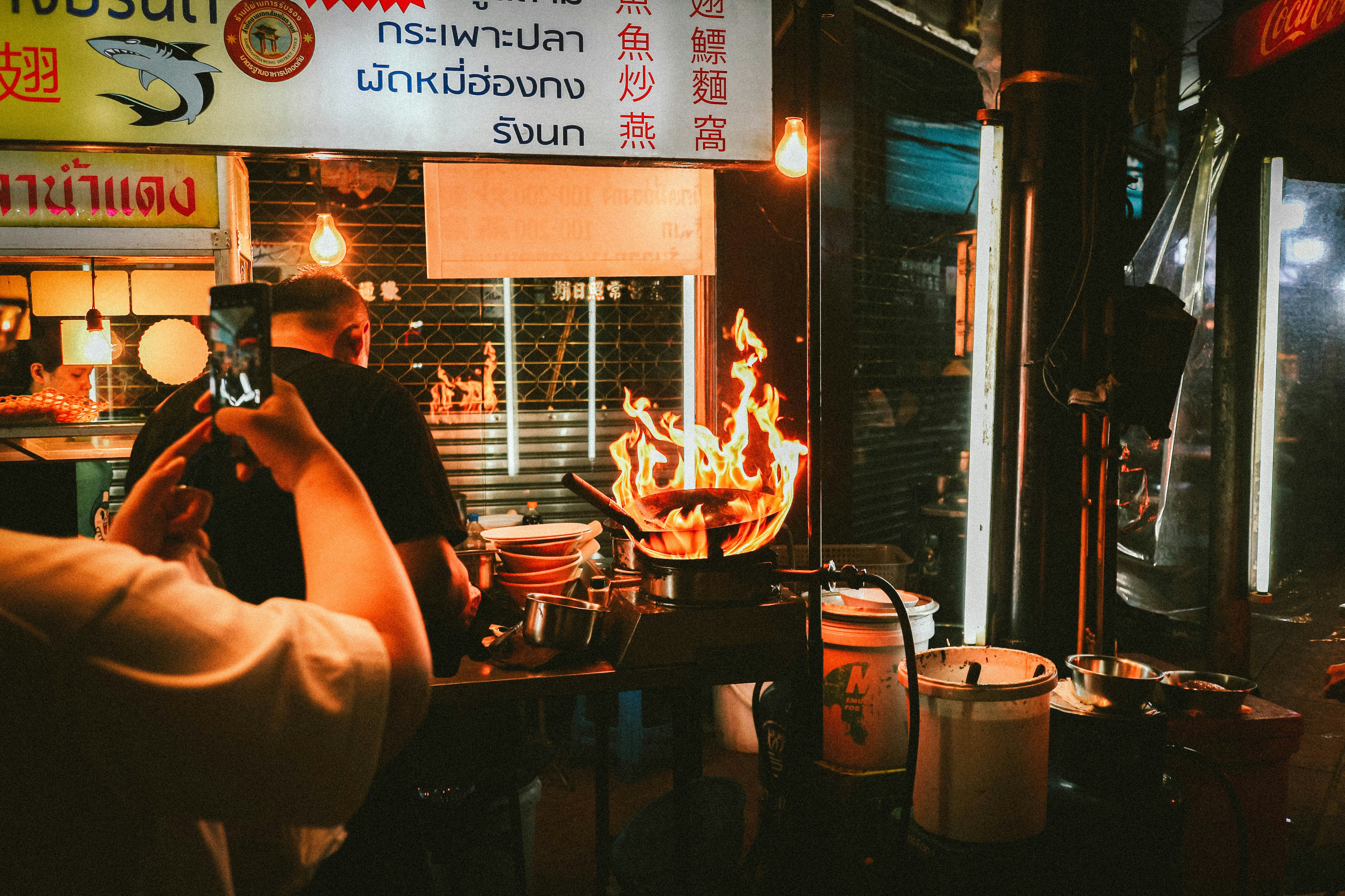 A man cooking food in a restaurant with a fire in the background
