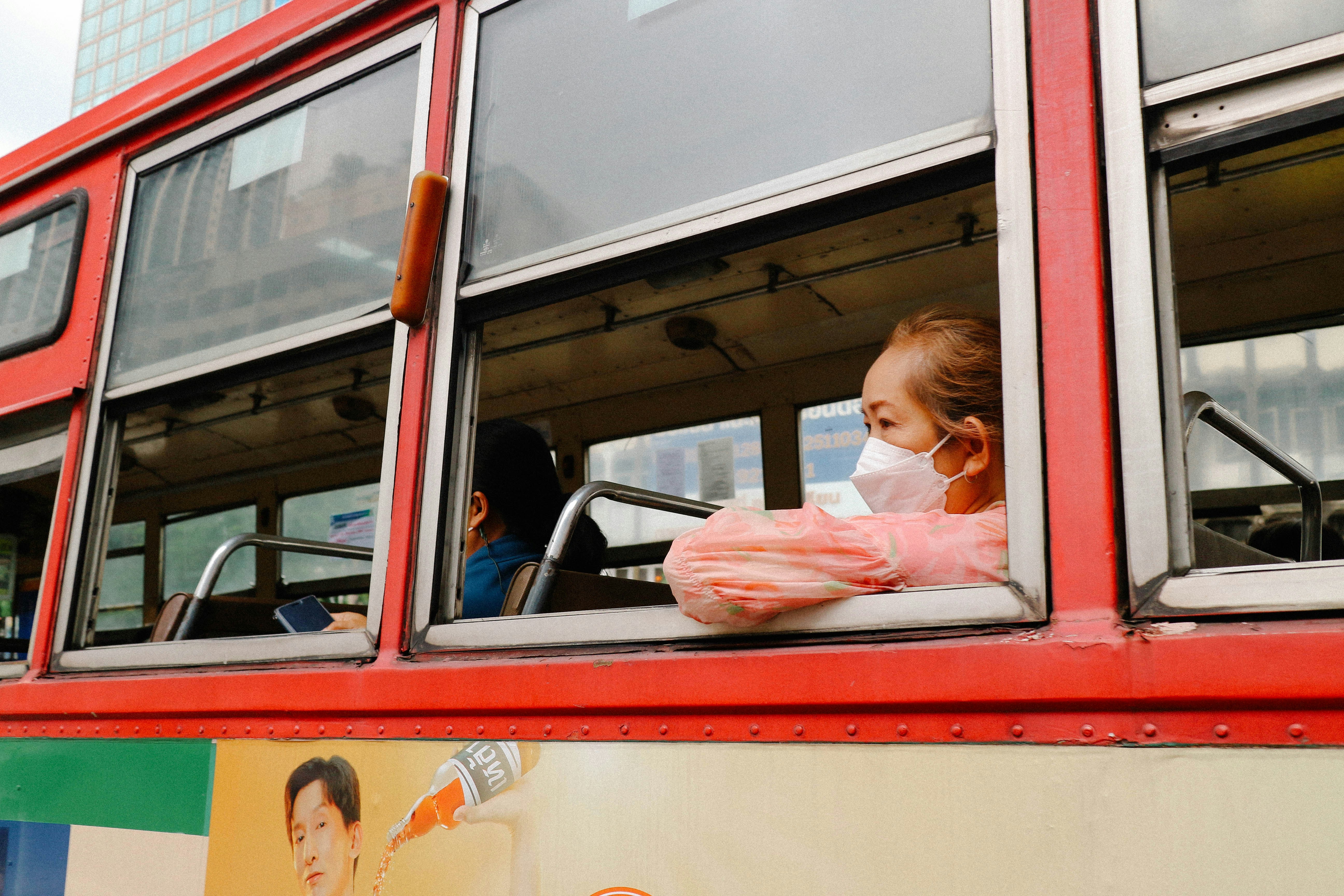 A young girl looks out the window of a double decker bus