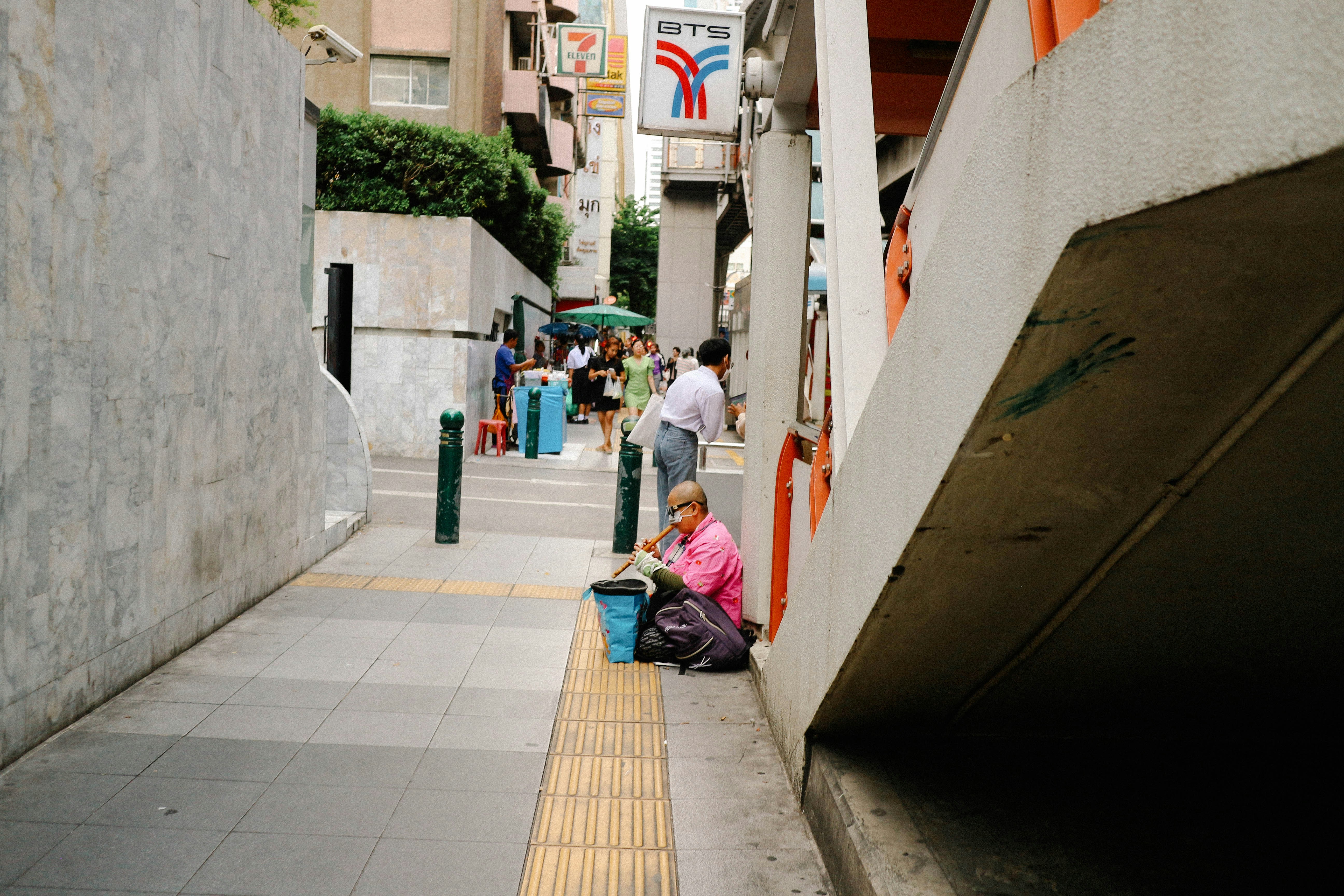 A group of people walking down a street next to tall buildings