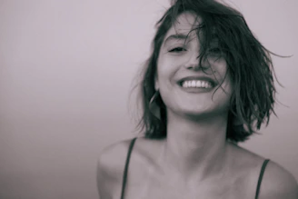 A woman with wet hair smiling and holding a cell phone