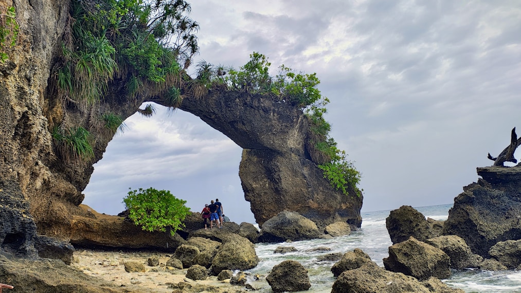 A rocky beach with a large arch in the middle of it