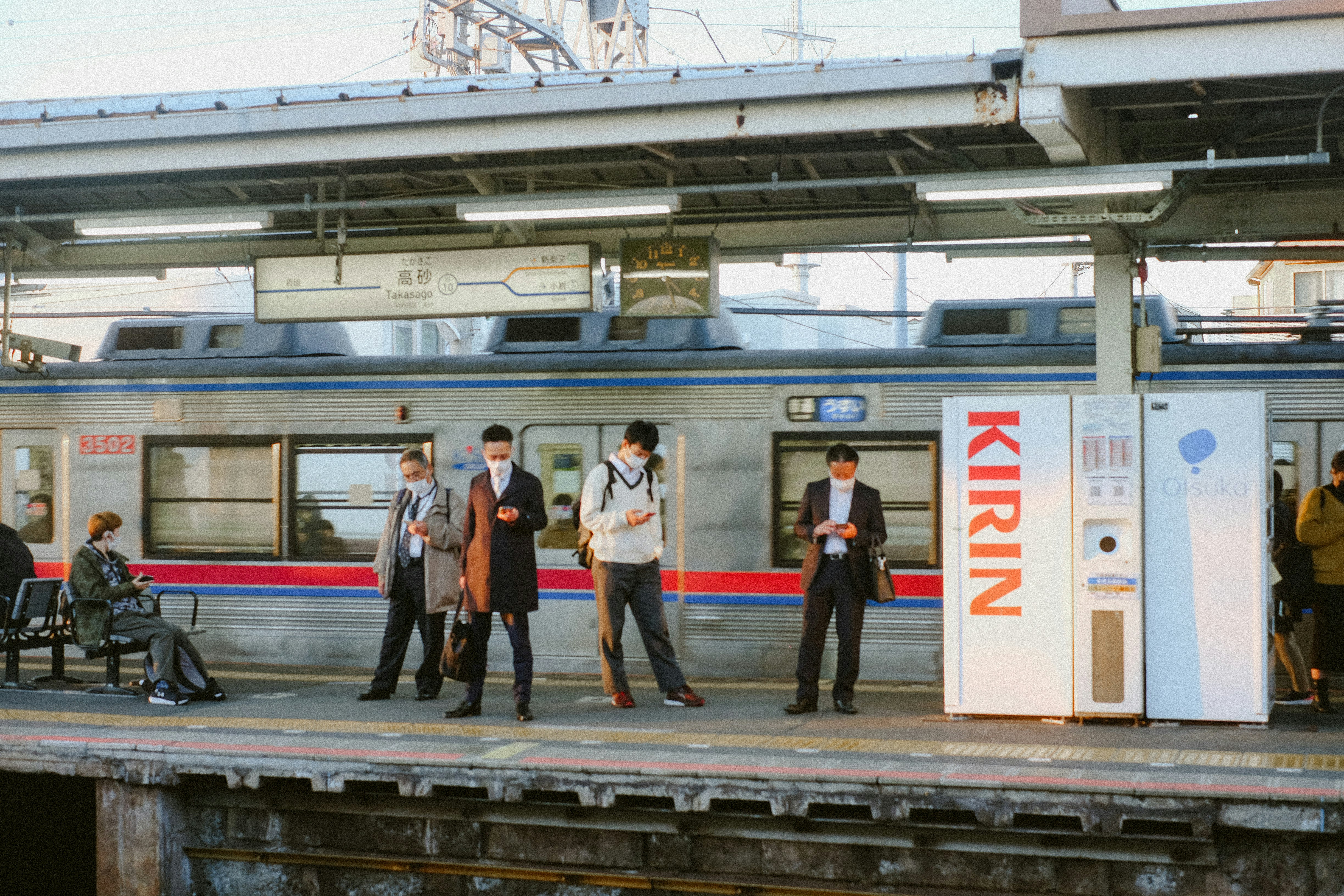 A group of people standing on a platform next to a train, A metro in Tokyo