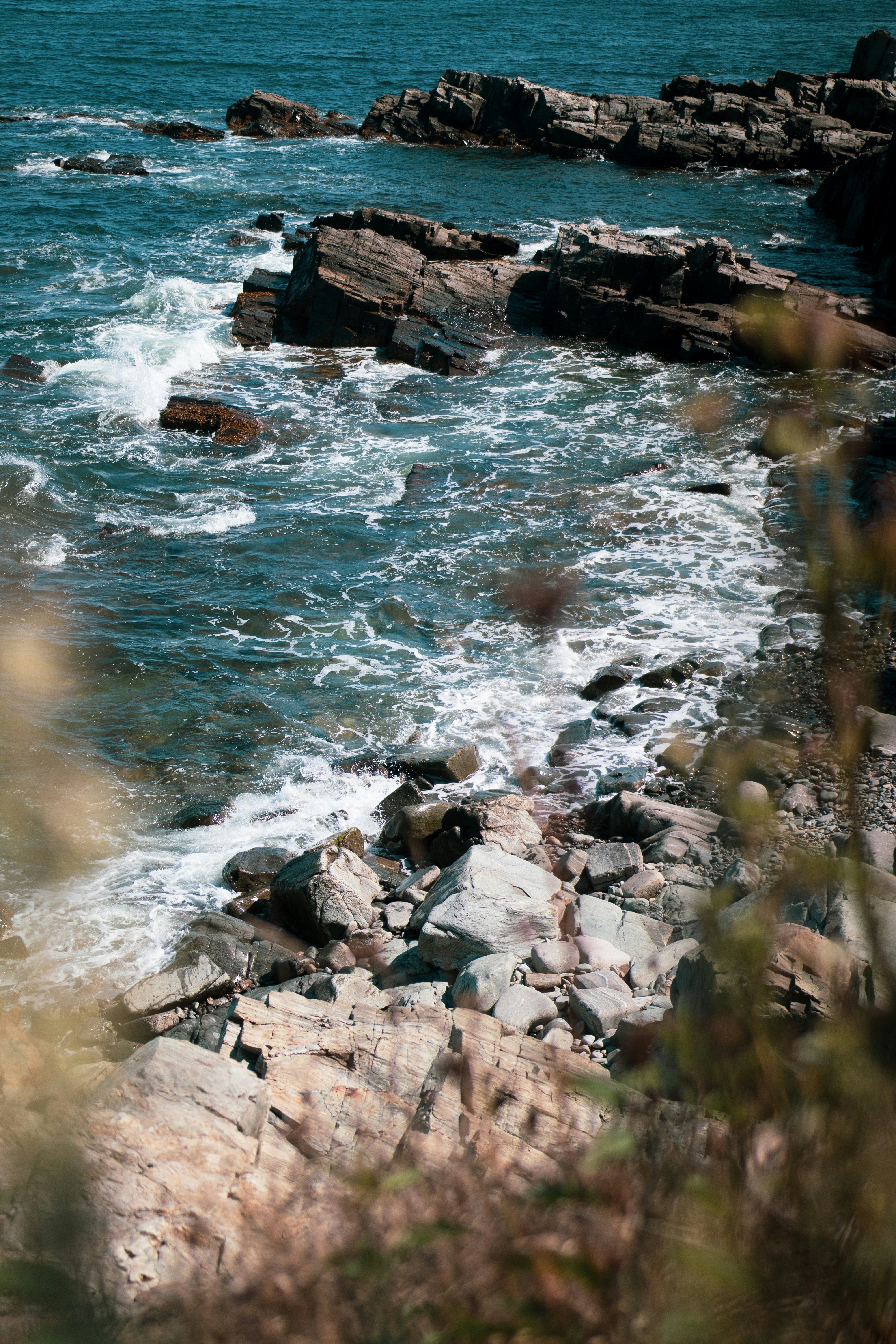 A man standing on top of a rocky beach next to the ocean