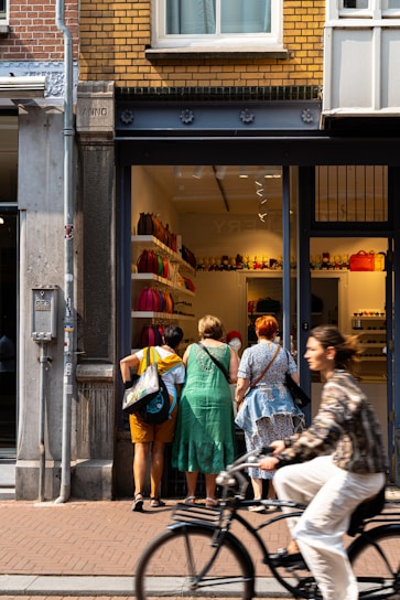 A man riding a bike past a store front