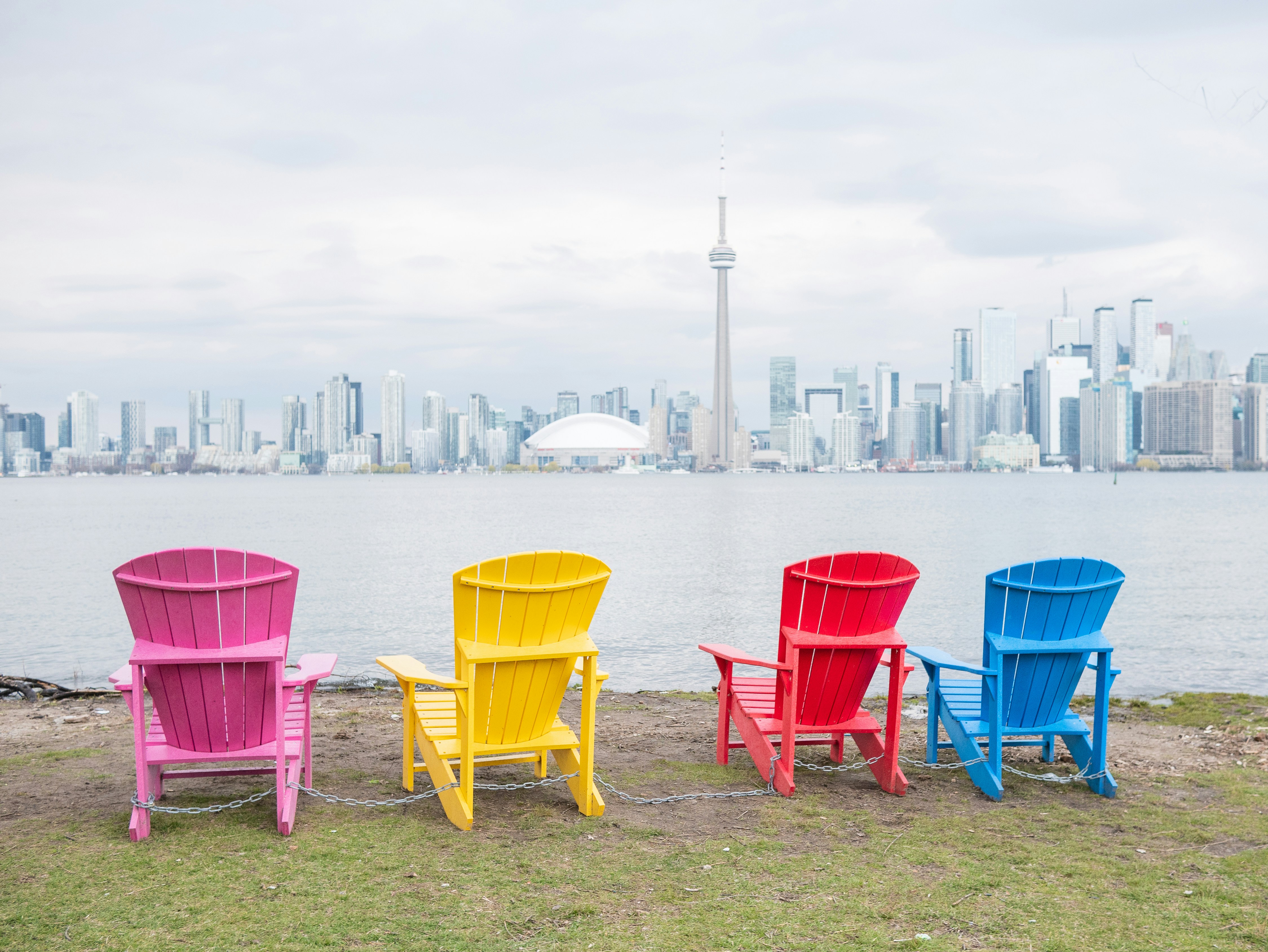 A row of colorful chairs sitting in front of a body of water