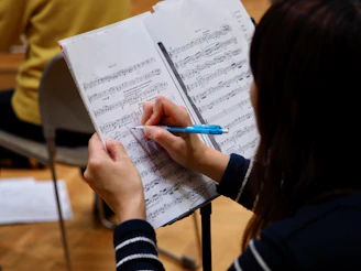 A woman is writing on a sheet of music