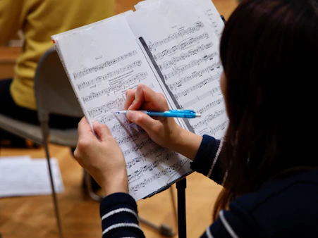 A woman is writing on a sheet of music