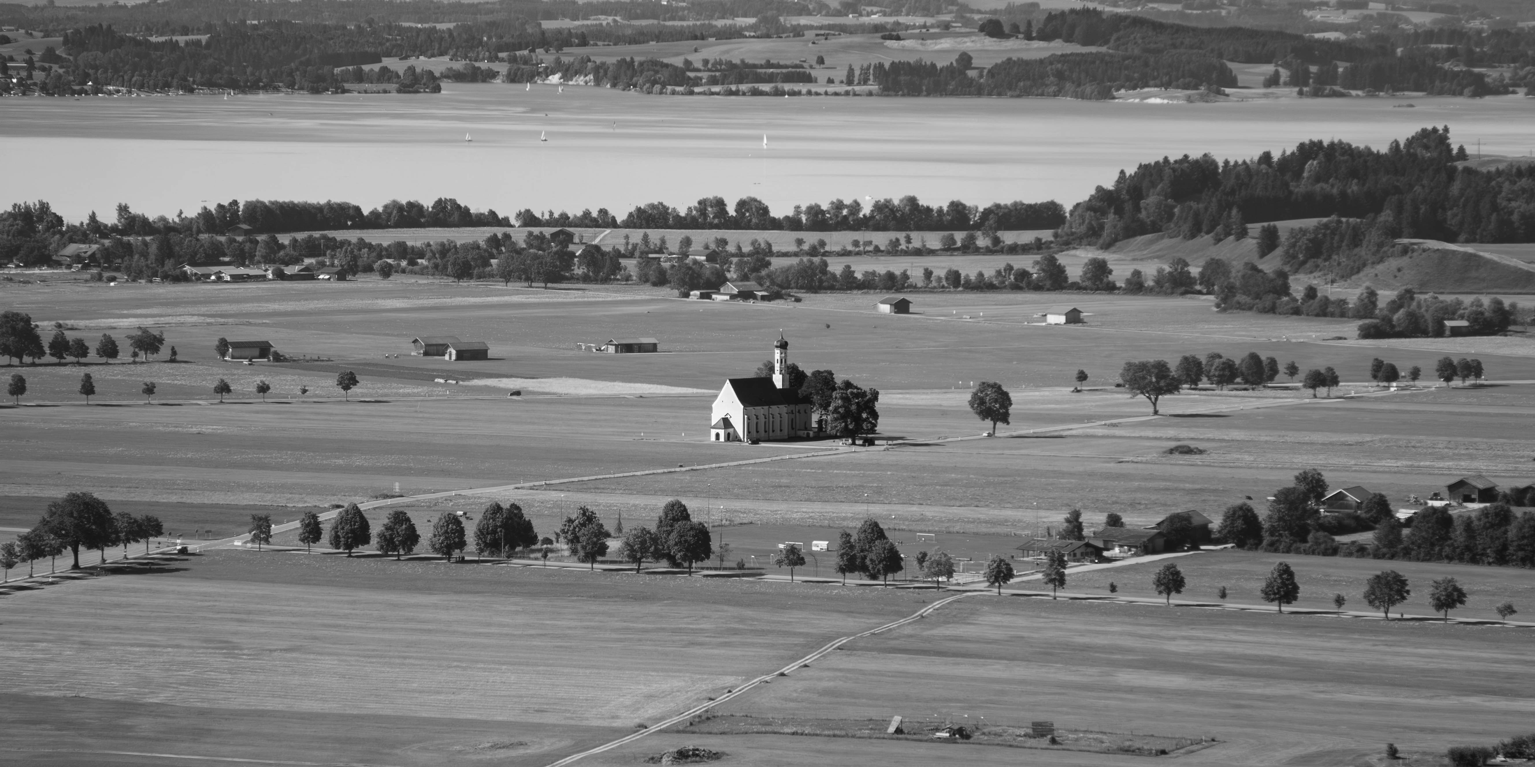 Uma foto em preto e branco de uma fazenda com um lago ao fundo