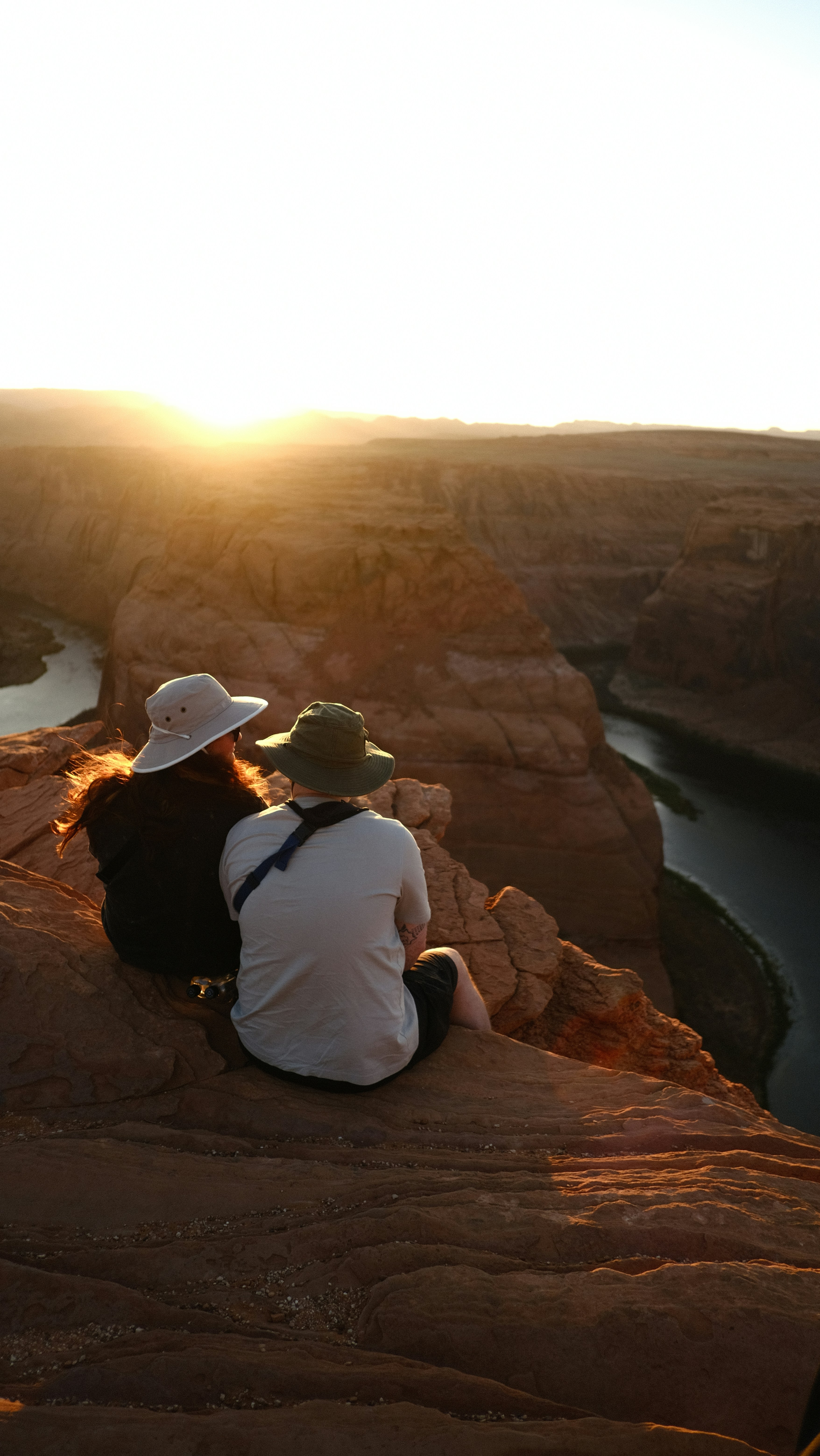 A couple of people sitting on top of a cliff photo – Free Horseshoe ...