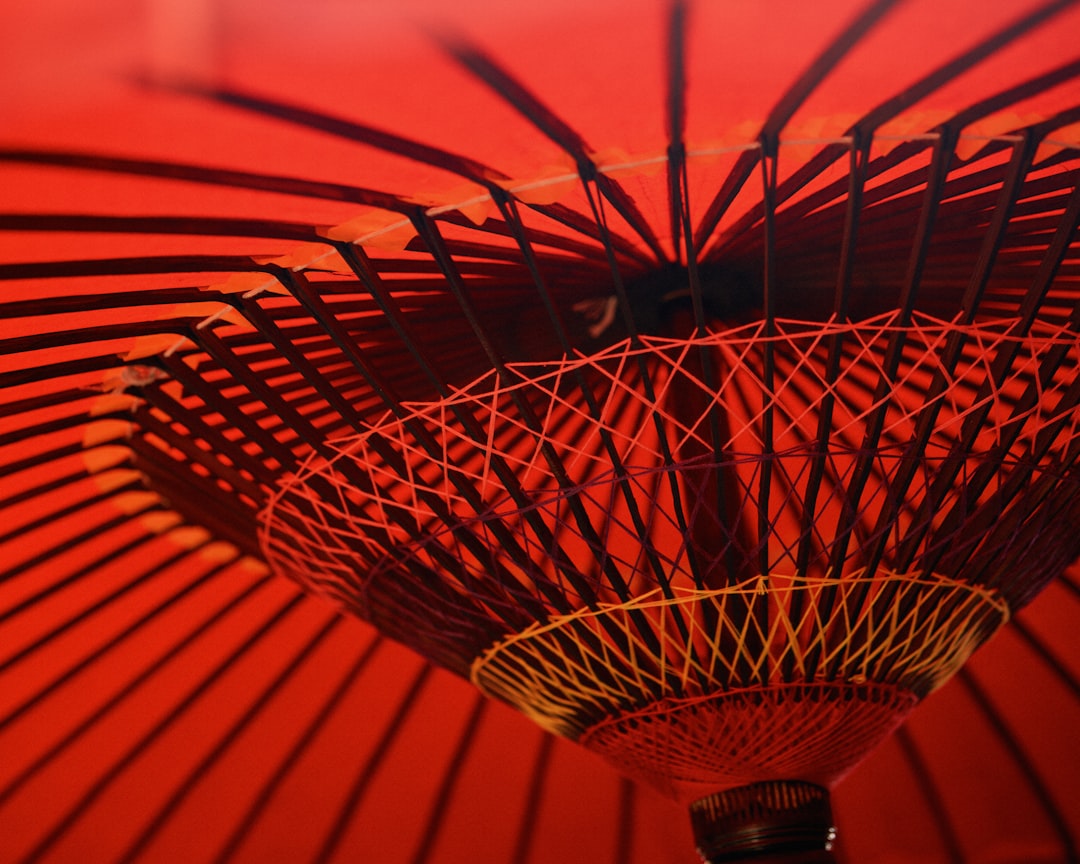 A close up of an umbrella with a red background, red umbrella