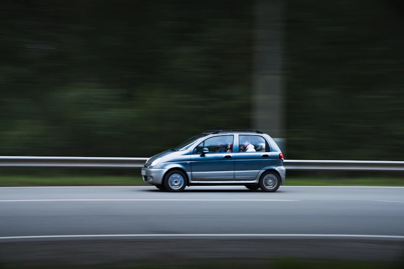 Small blue car driving down a road