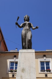 A statue of a woman holding a flower in front of a building