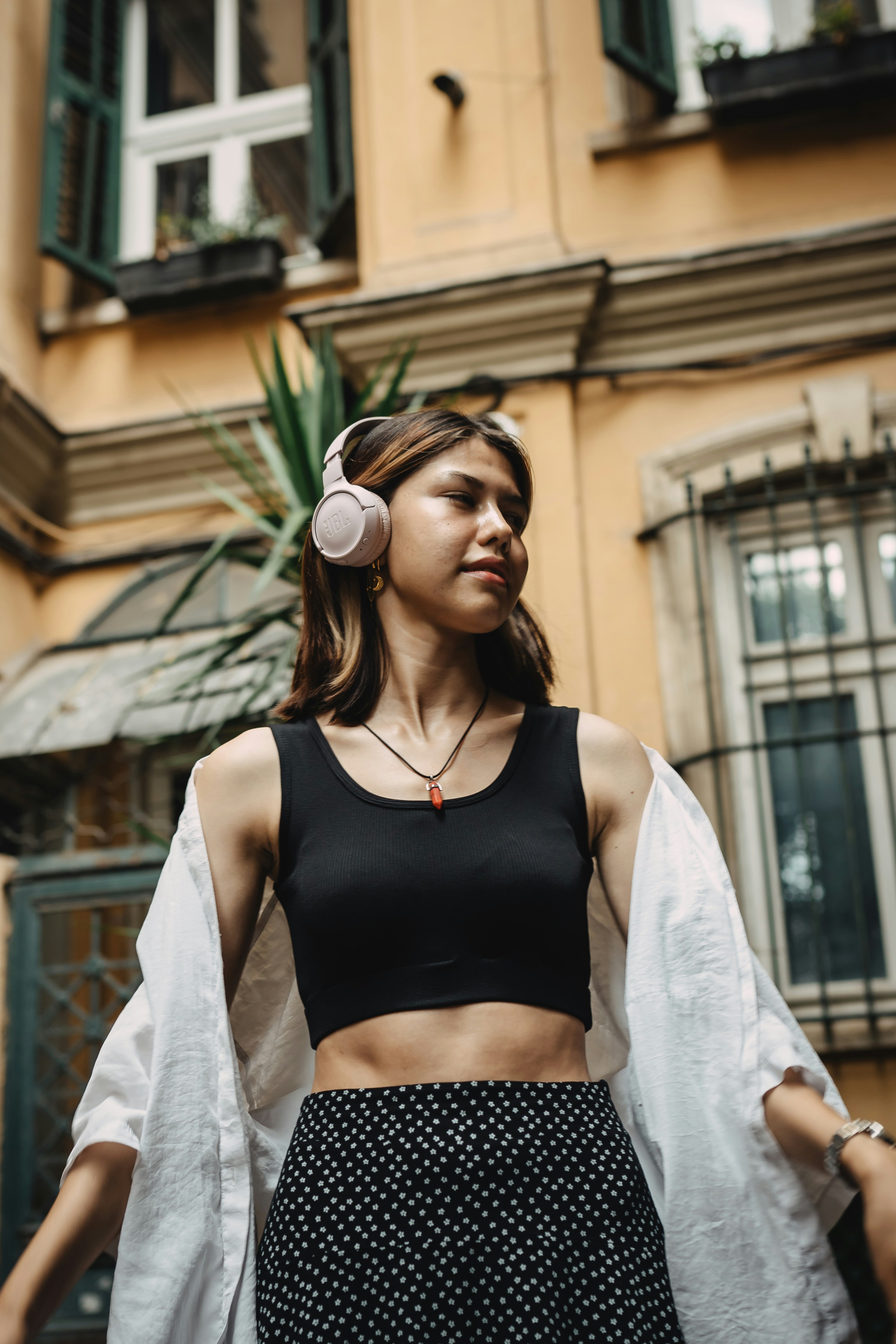 A woman wearing headphones standing in front of a building