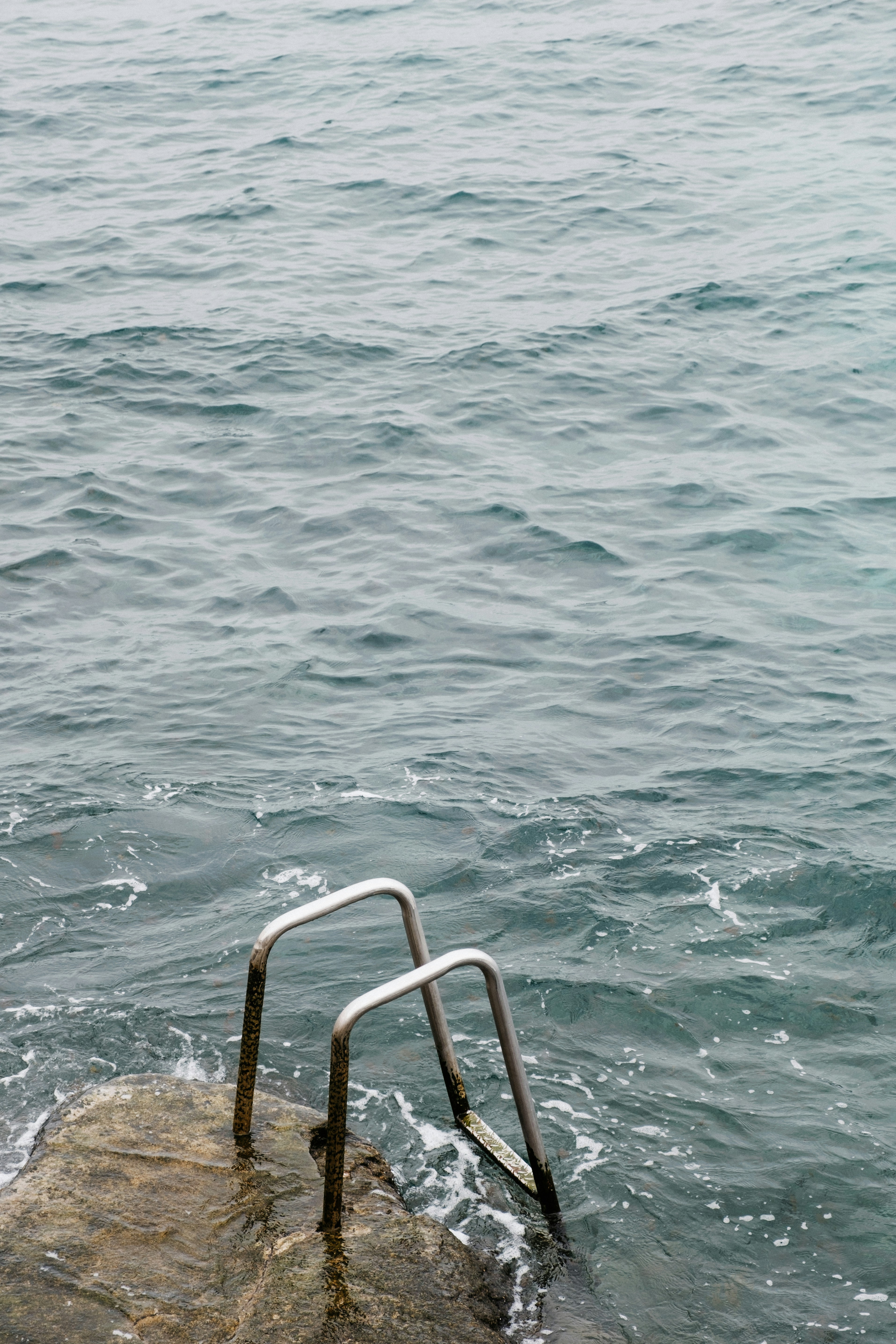 A man standing on top of a rock in the ocean
