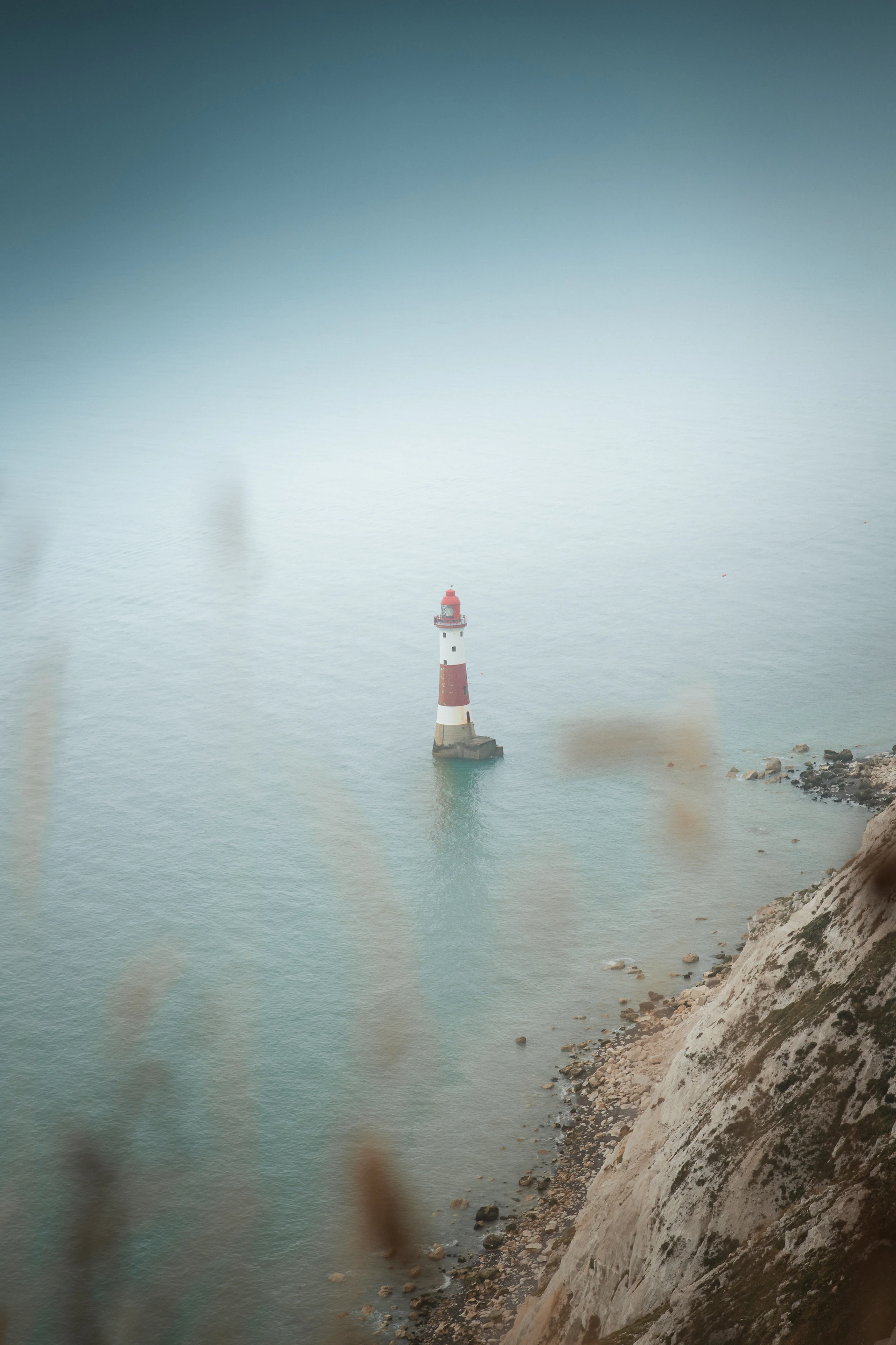 A red and white light house sitting on top of a body of water
