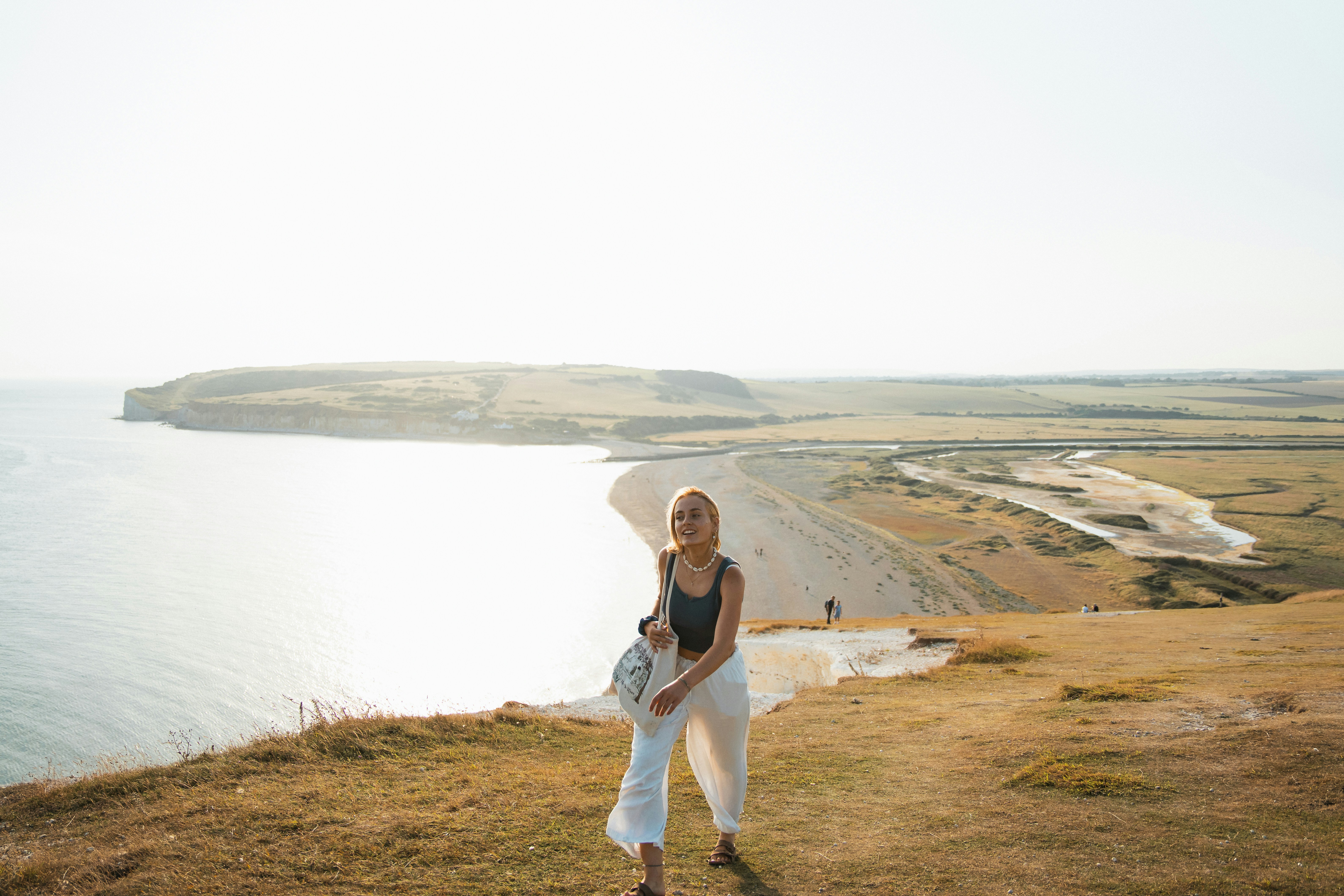 A woman standing on top of a hill next to the ocean