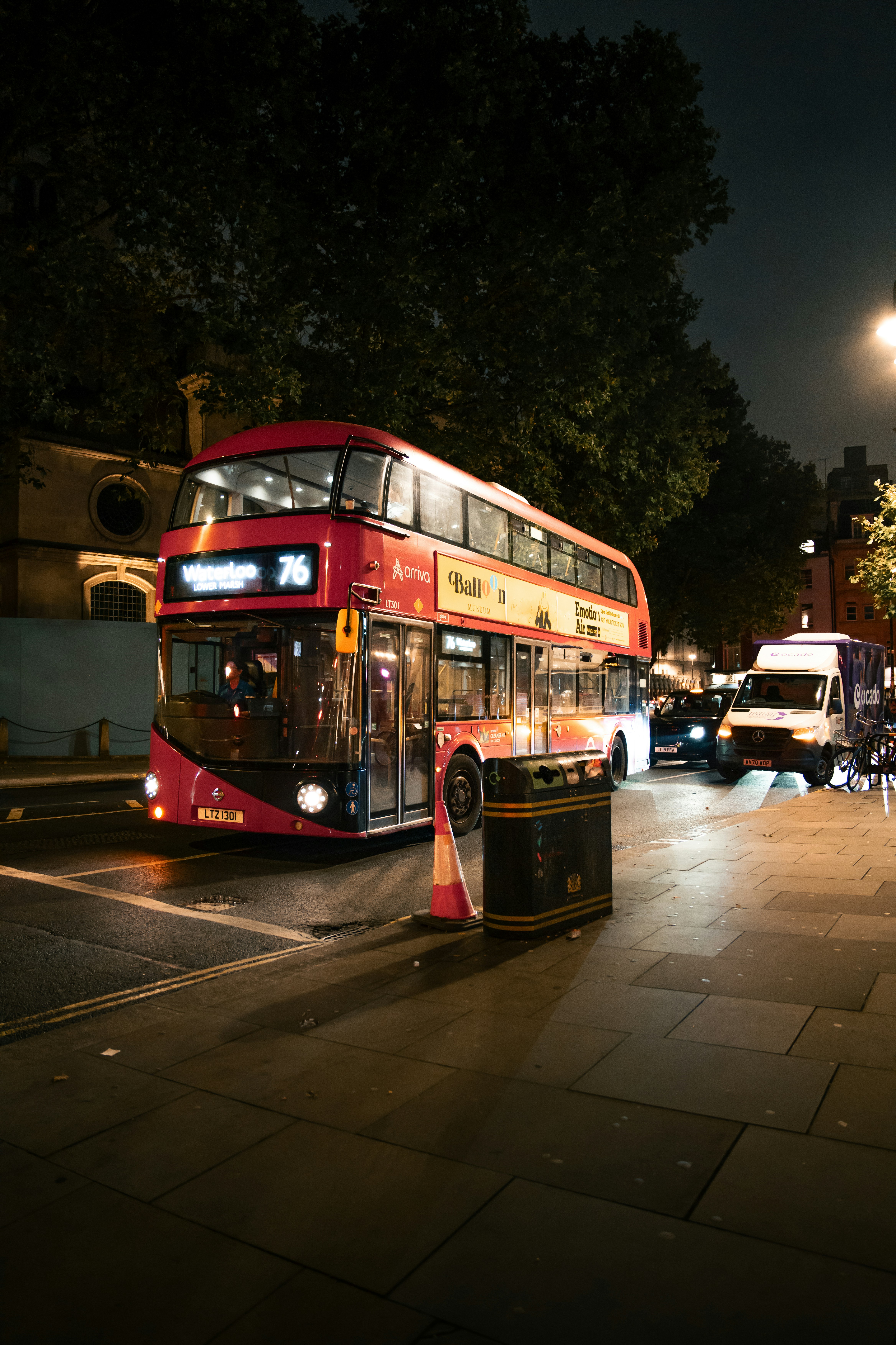 A red double decker bus driving down a street