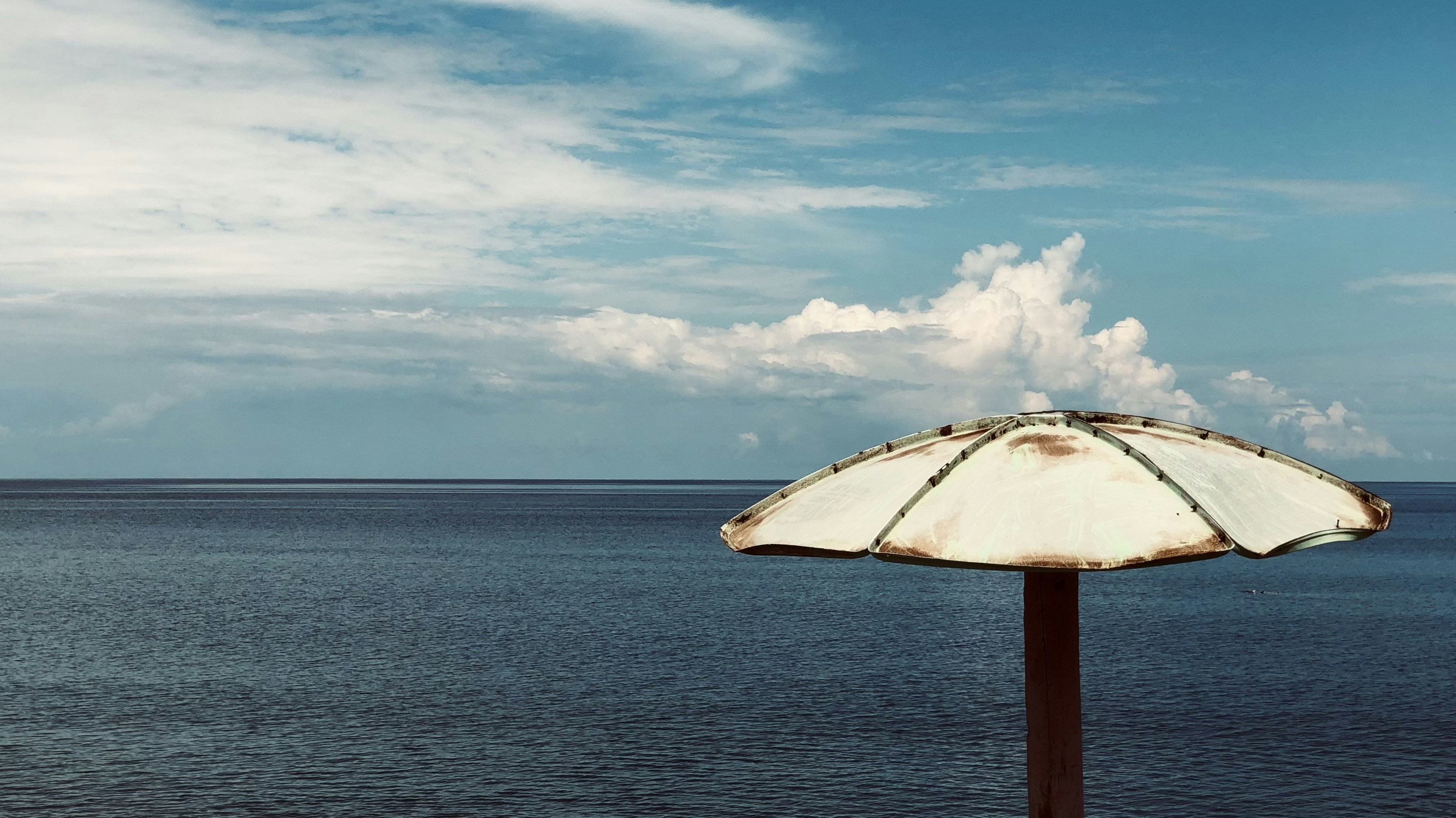 A white umbrella sitting on top of a wooden pole