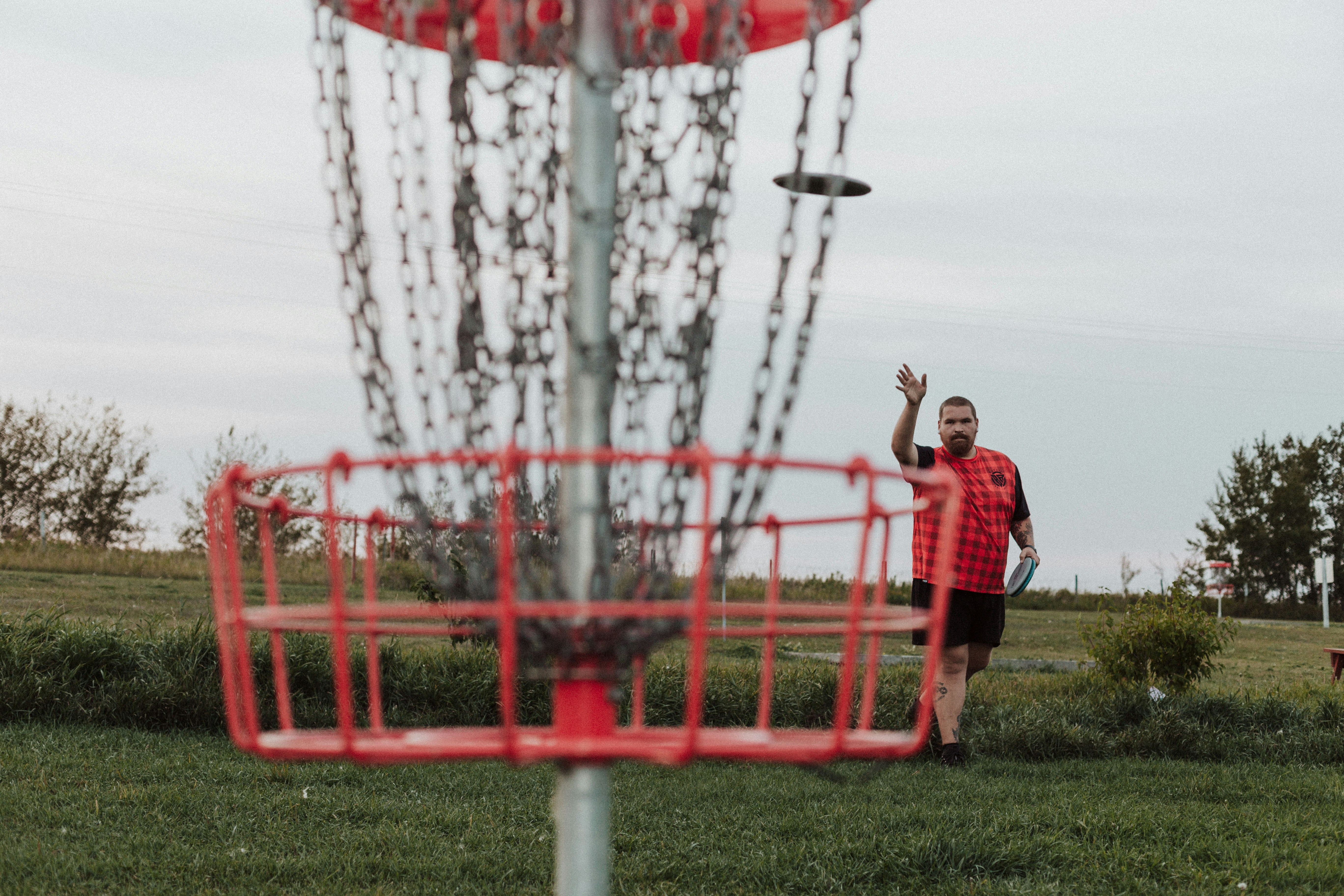 A man throwing a frisbee into a metal basket
