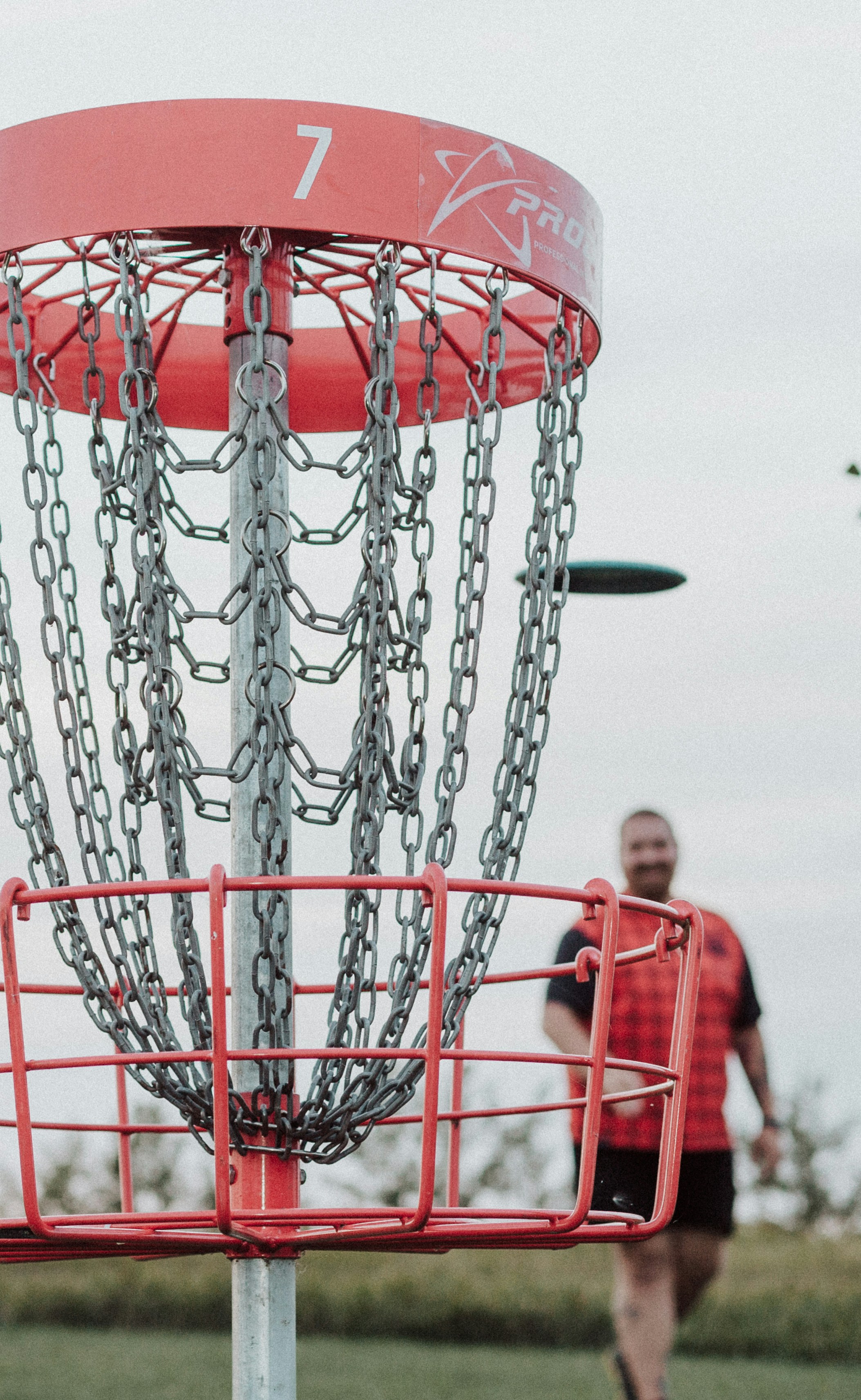 A man is throwing a frisbee into a chain - link basket