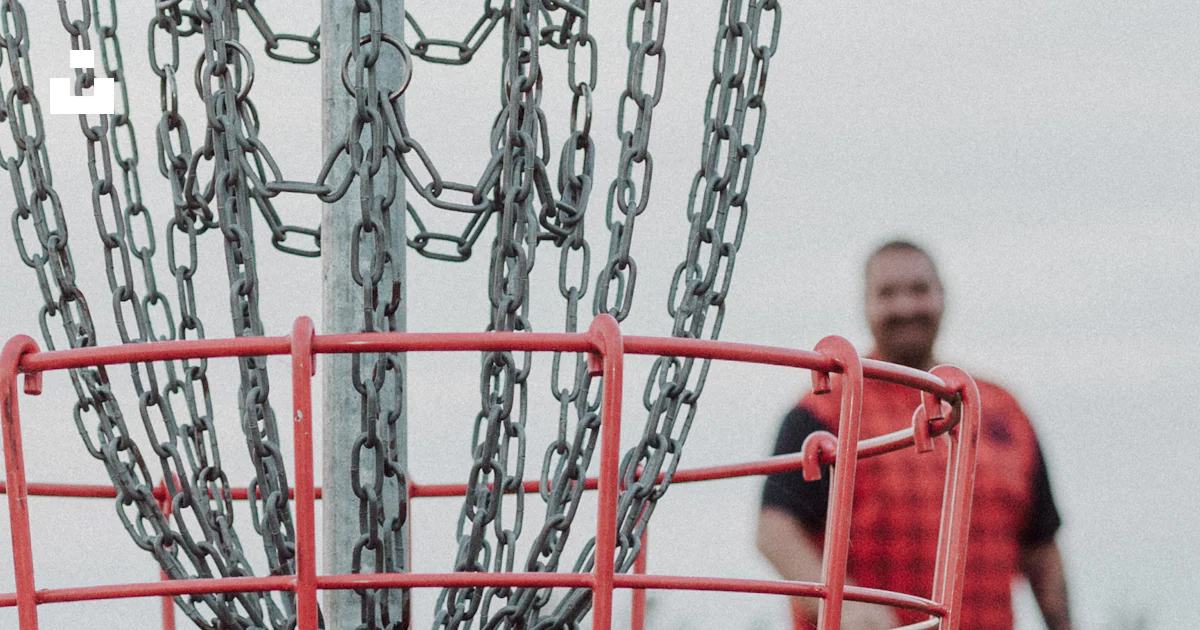A man is throwing a frisbee into a chain - link basket photo – Free ...