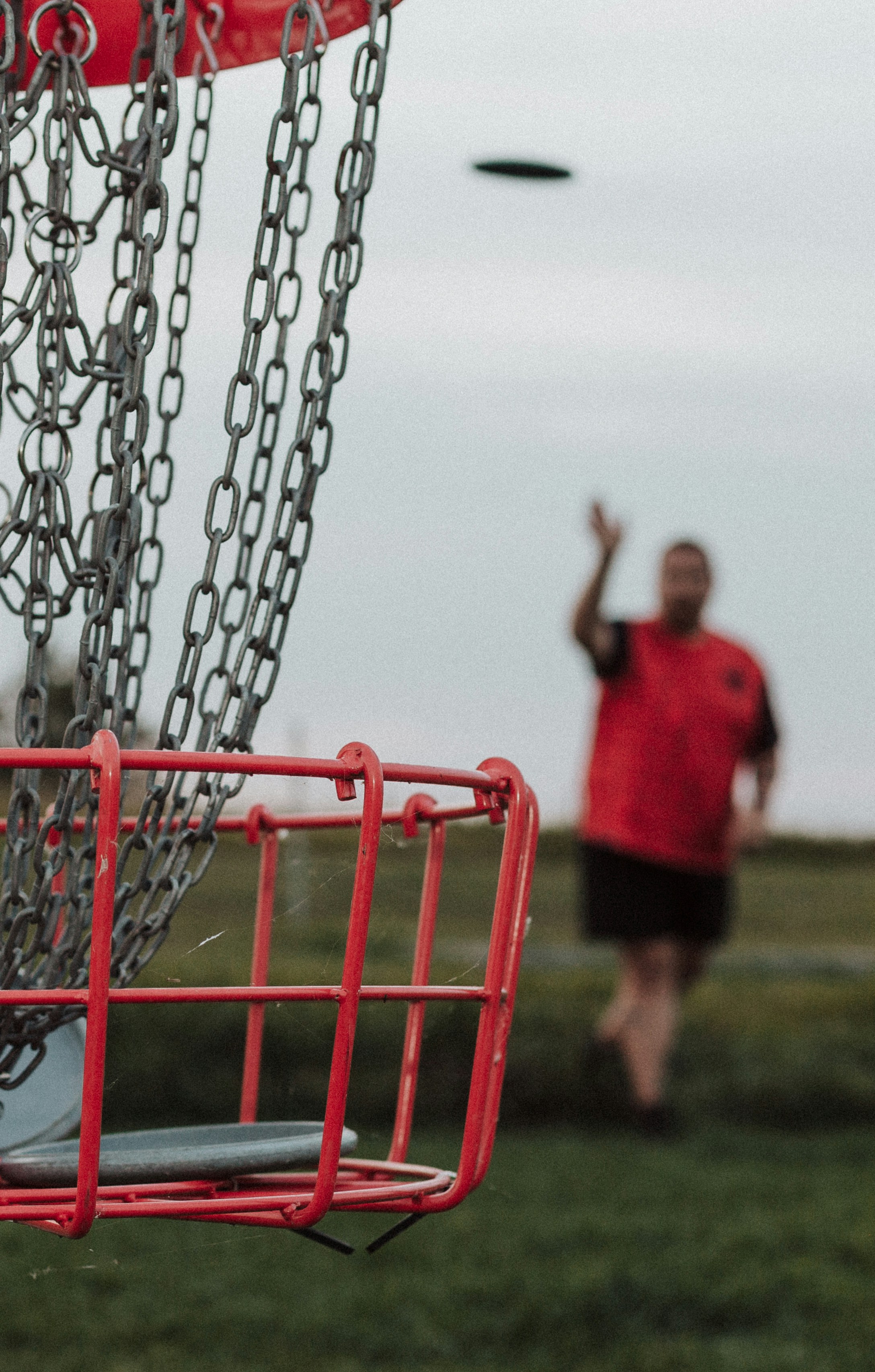 A man throwing a frisbee into a metal basket