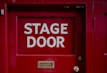 A red door with a sign that says stage door