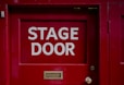 A red door with a sign that says stage door
