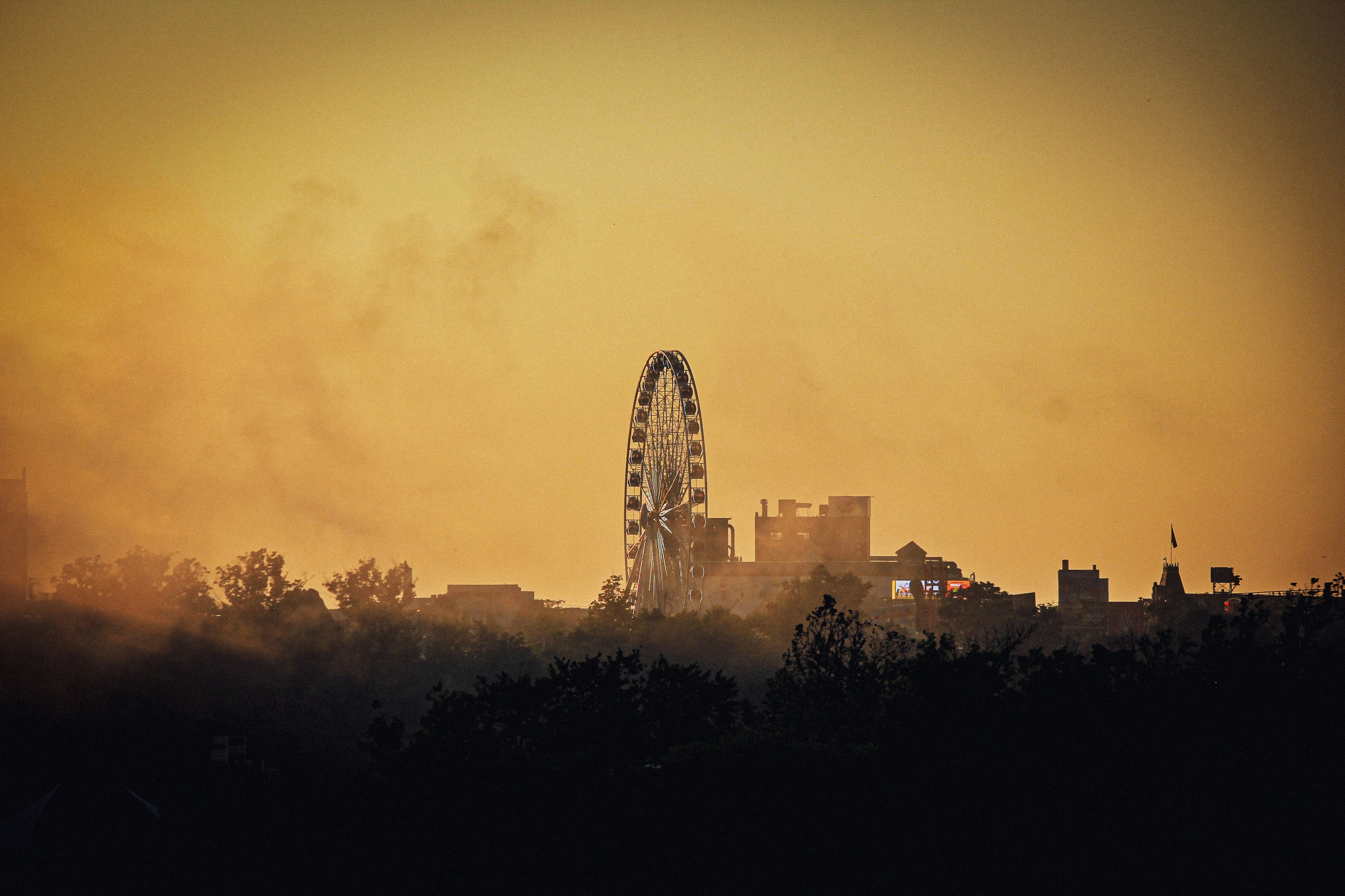 Una noria a lo lejos con edificios al fondo