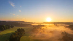The sun is setting over a foggy valley