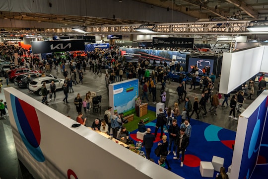 A crowd of people standing around a car show