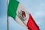 The mexican flag is flying high in the sky