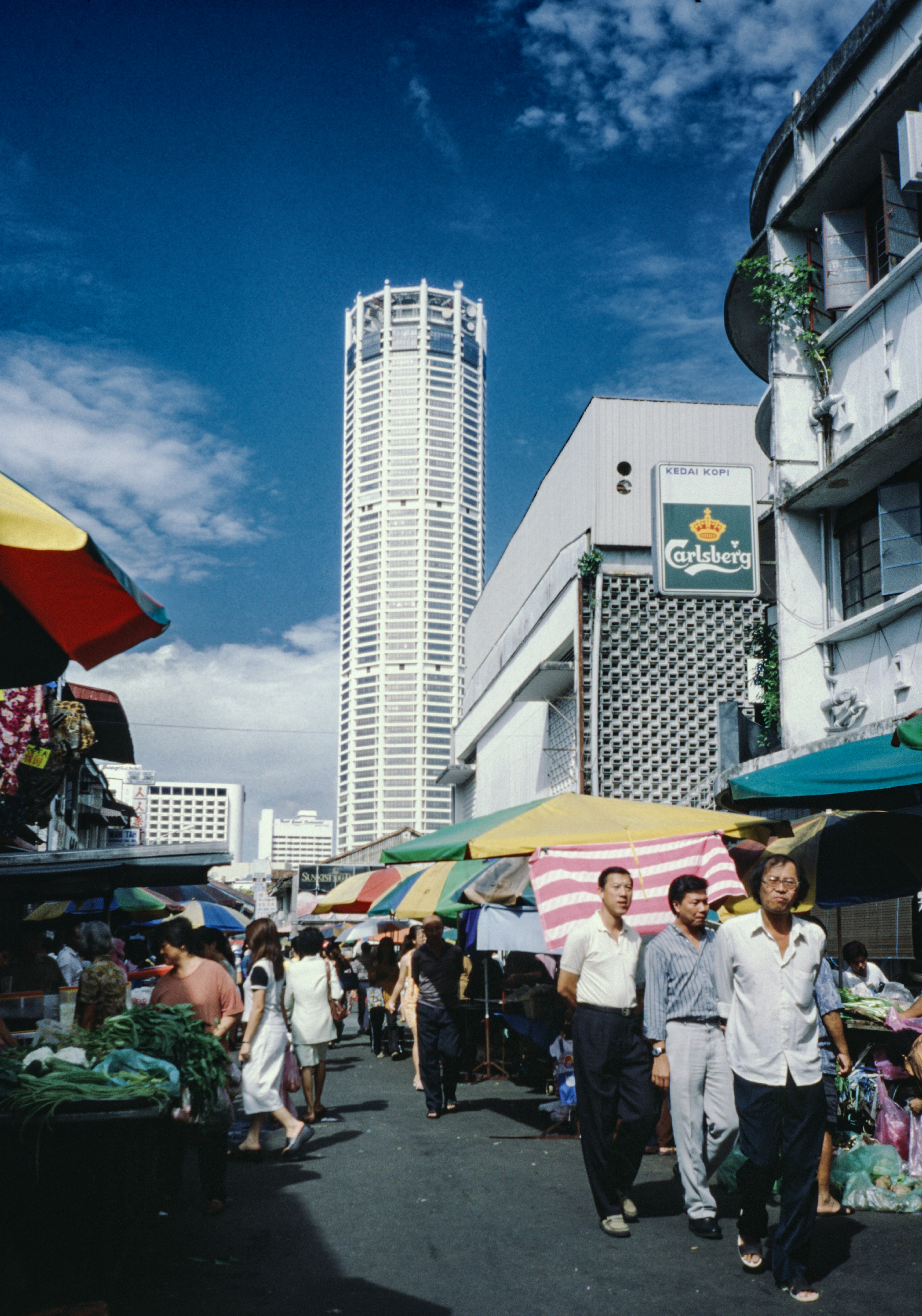 A group of people walking down a street next to buildings