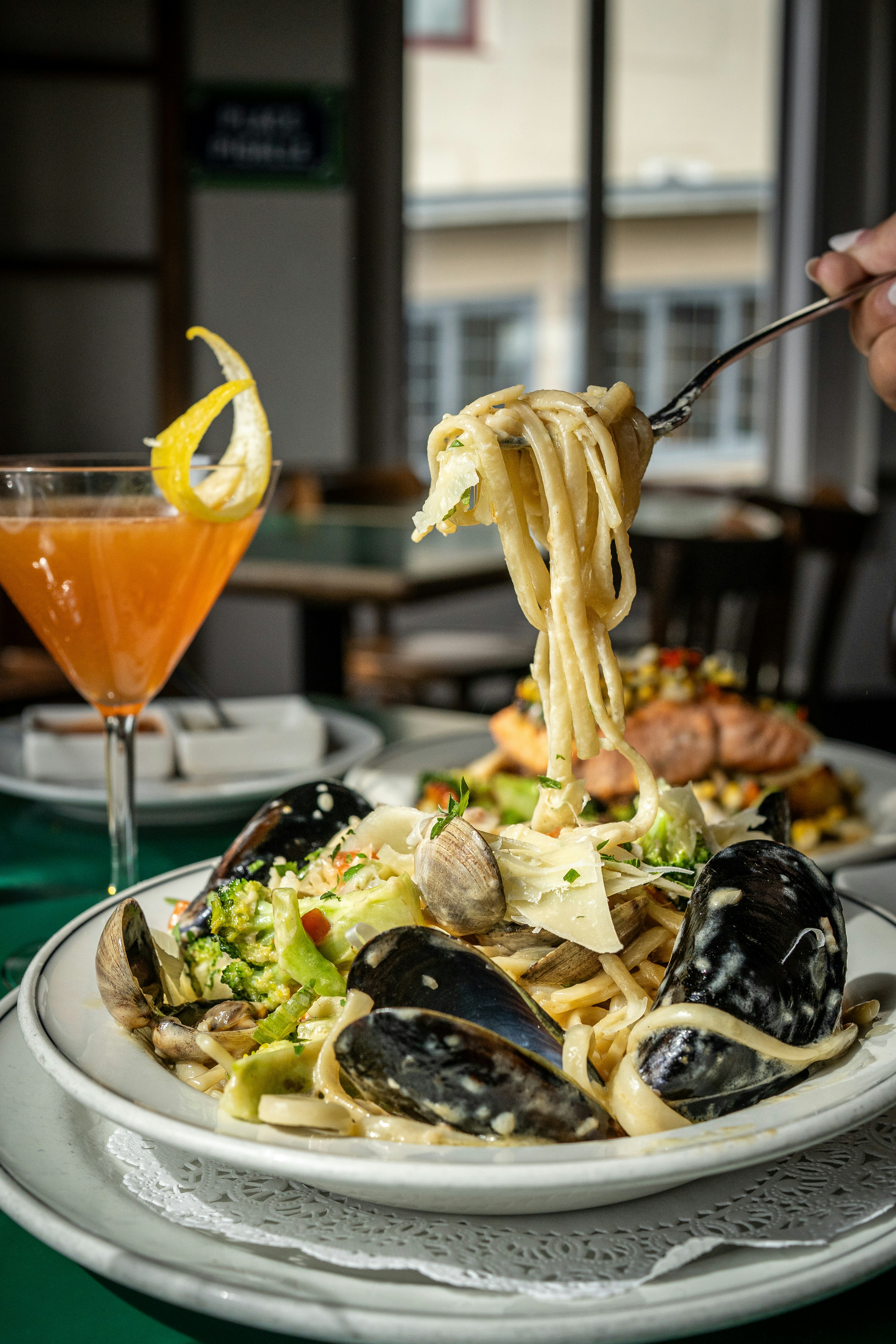 A plate of pasta with mussels and a glass of orange juice