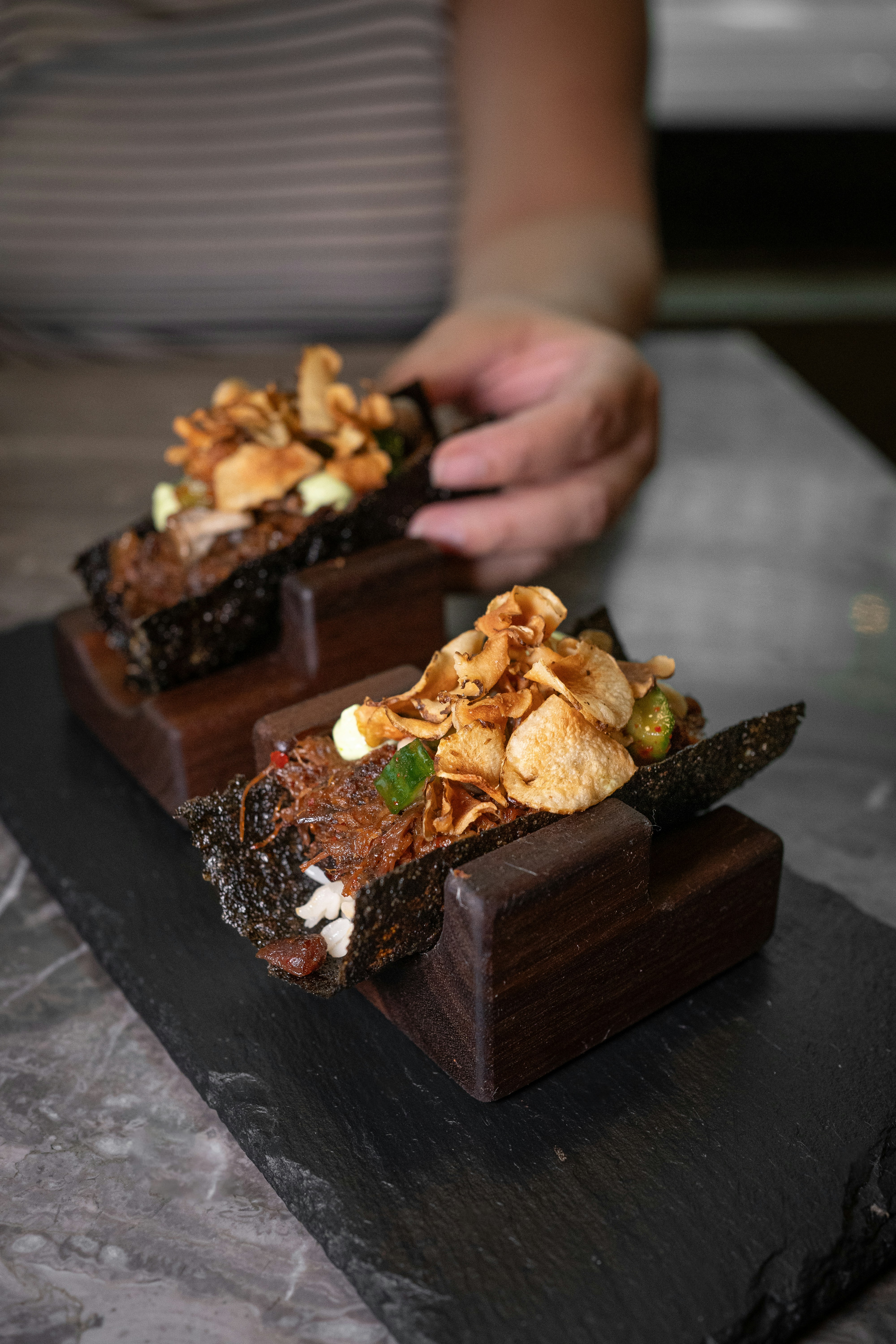 A person is holding a piece of chocolate dessert