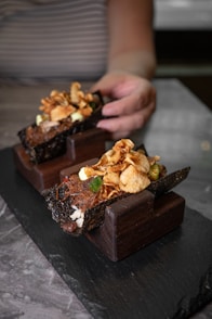 A person is holding a piece of chocolate dessert