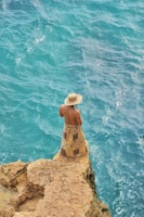 A person sitting on a rock near the ocean
