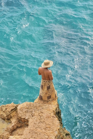 A person sitting on a rock near the ocean