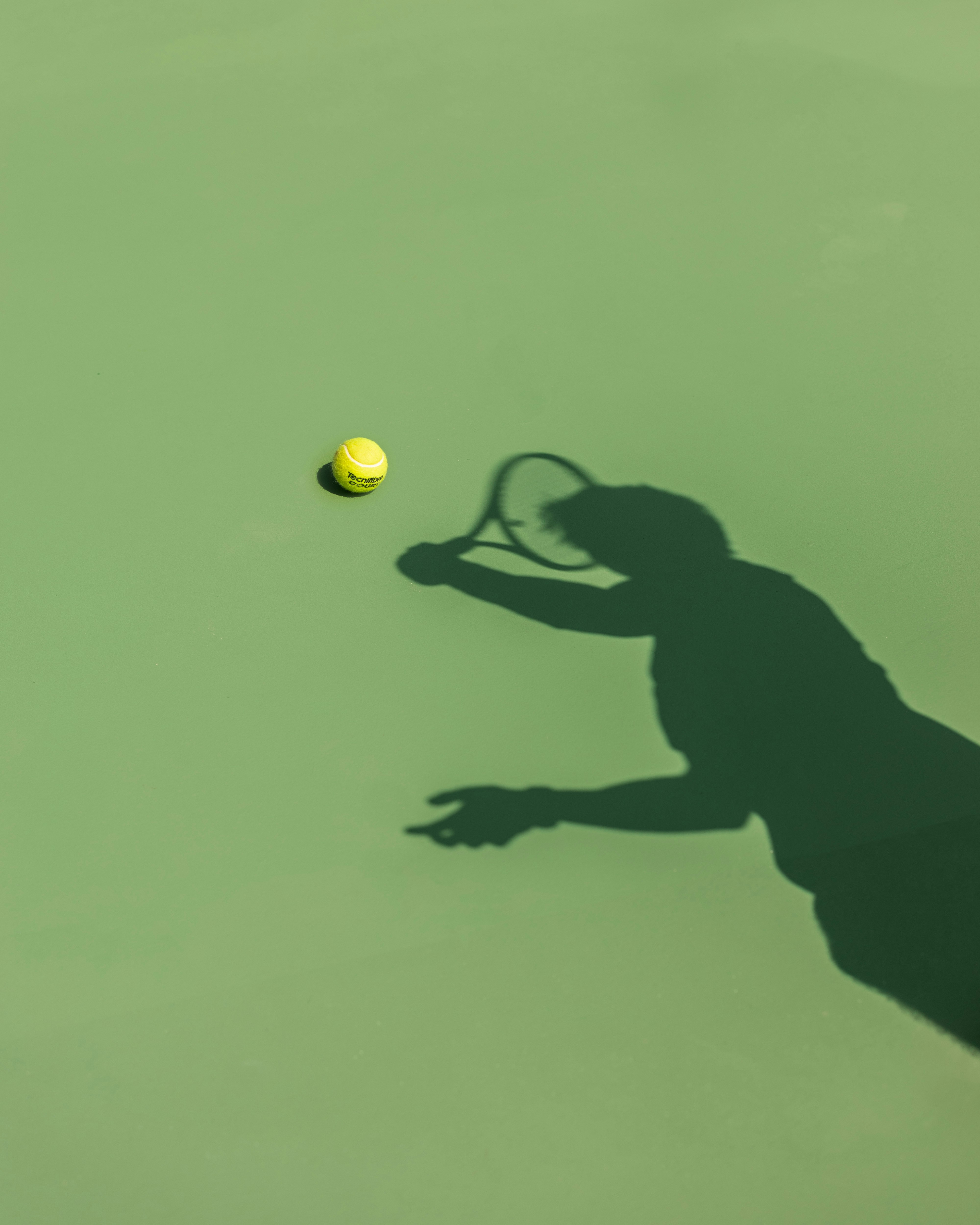 A shadow of a tennis player hitting a tennis ball